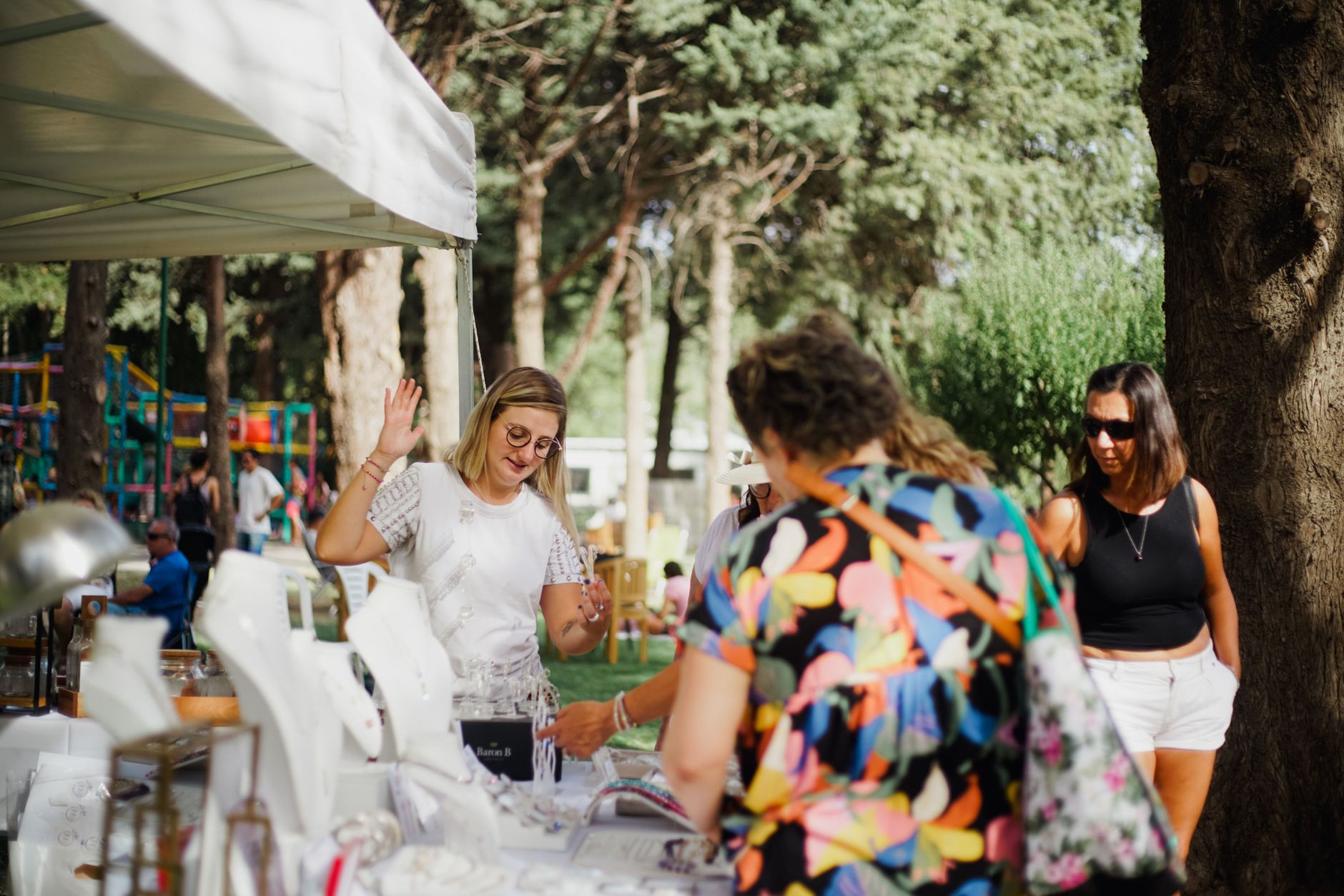 A small business owner serves visitors from a friendly market stall at a busy outdoor community event.