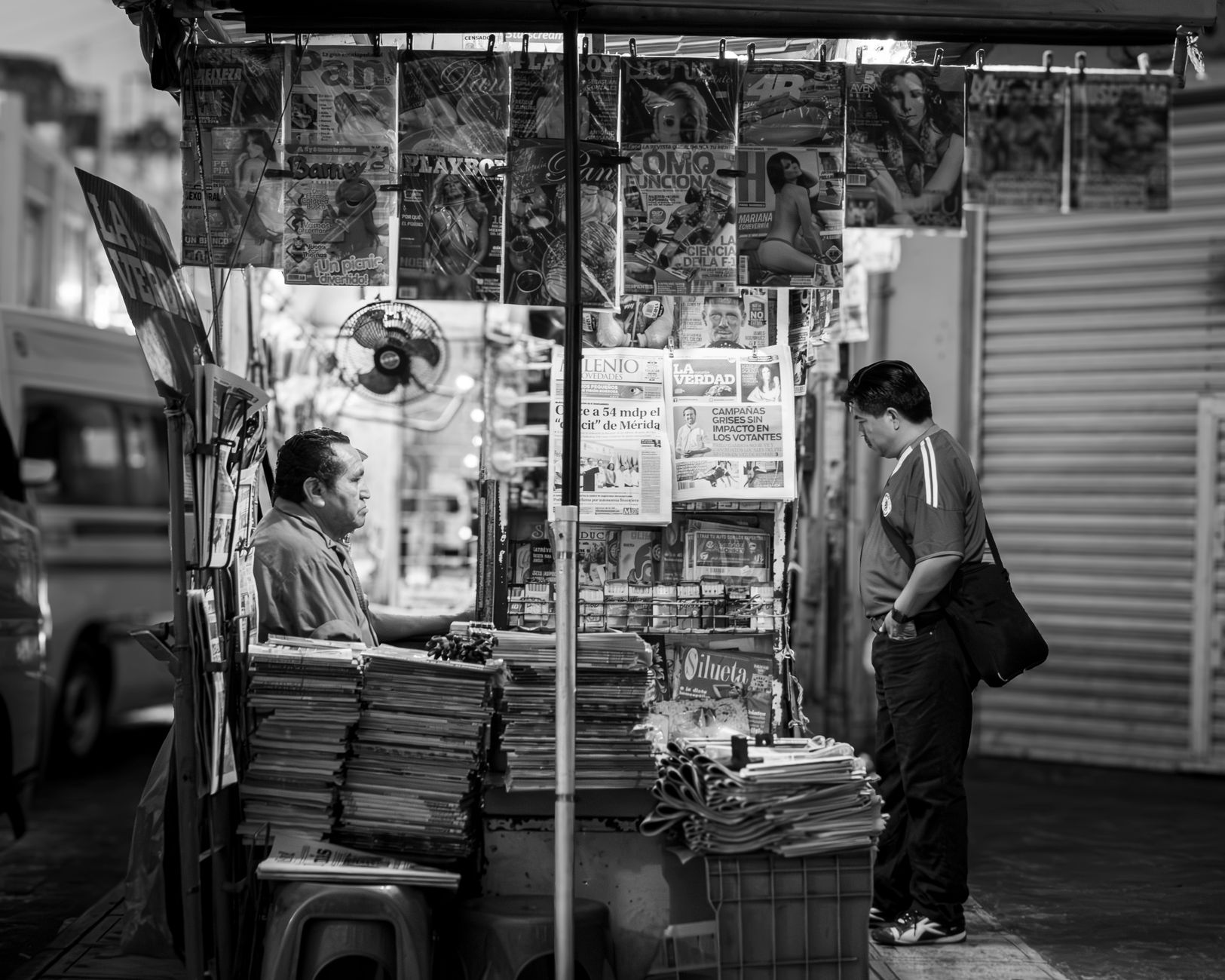 A local community newspaper and magazine sit open on a table beside a coffee, showing pages of neighbourhood business stories.