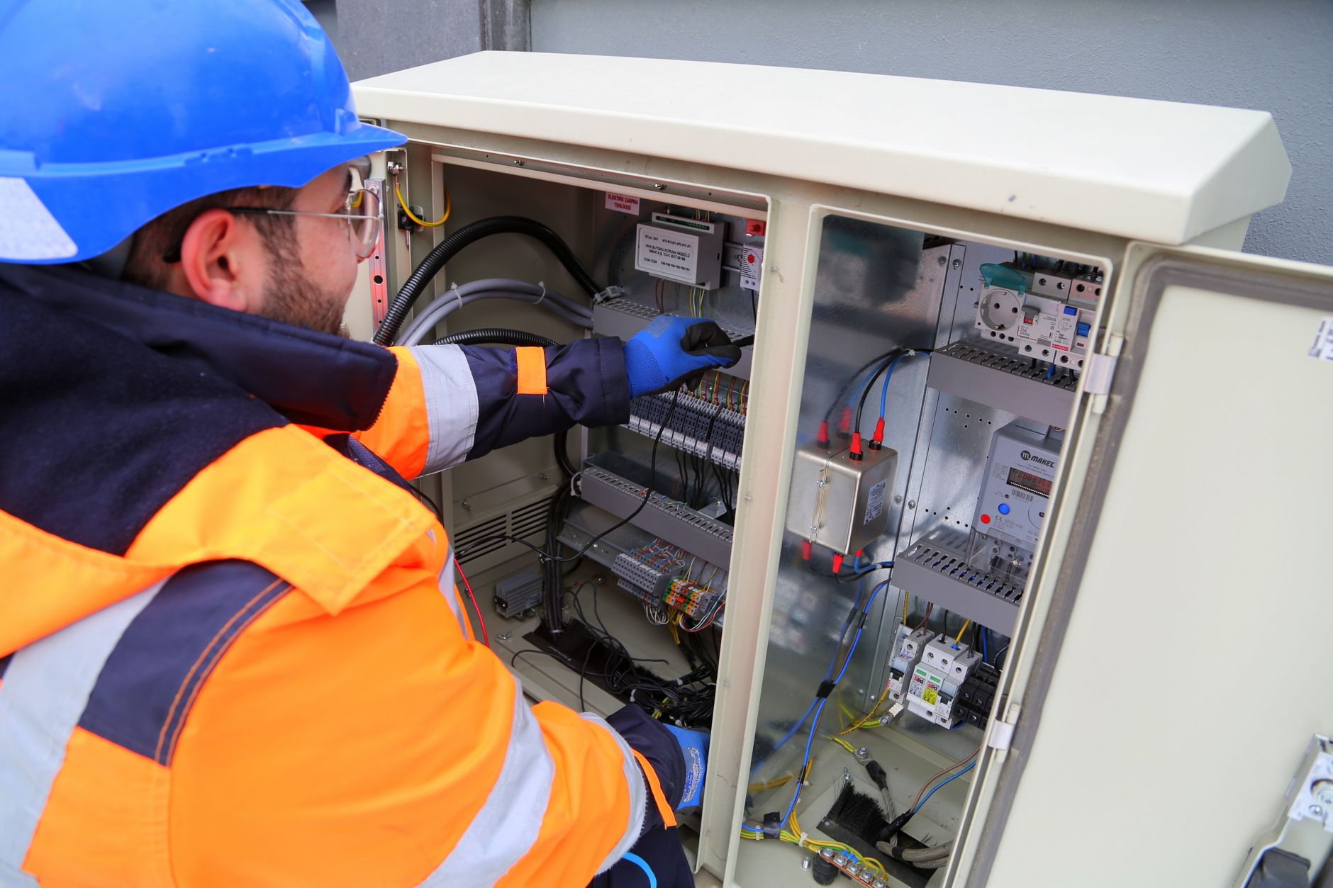 An electrician working on a customer's fuse box during a home visit
