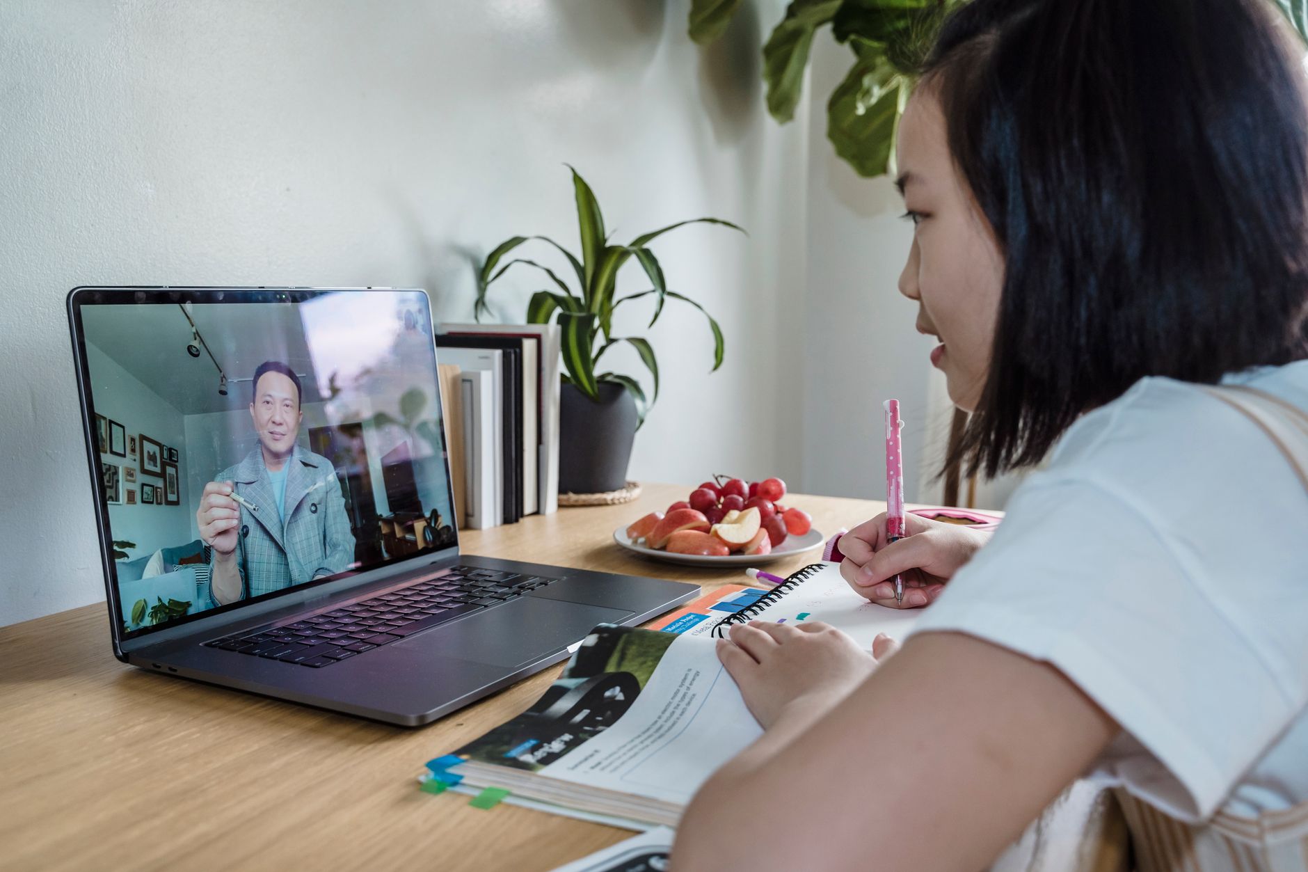 A student watches an online course lesson on a laptop while taking notes, completing a first module and reaching an early win.