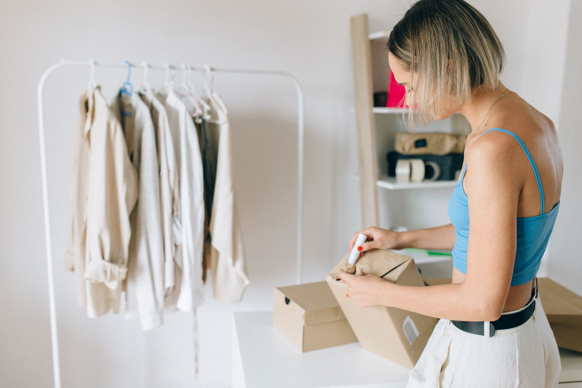 A seller folds a garment into a mailing parcel at a tidy home worktable, packing an online resale order ready to ship the same day.