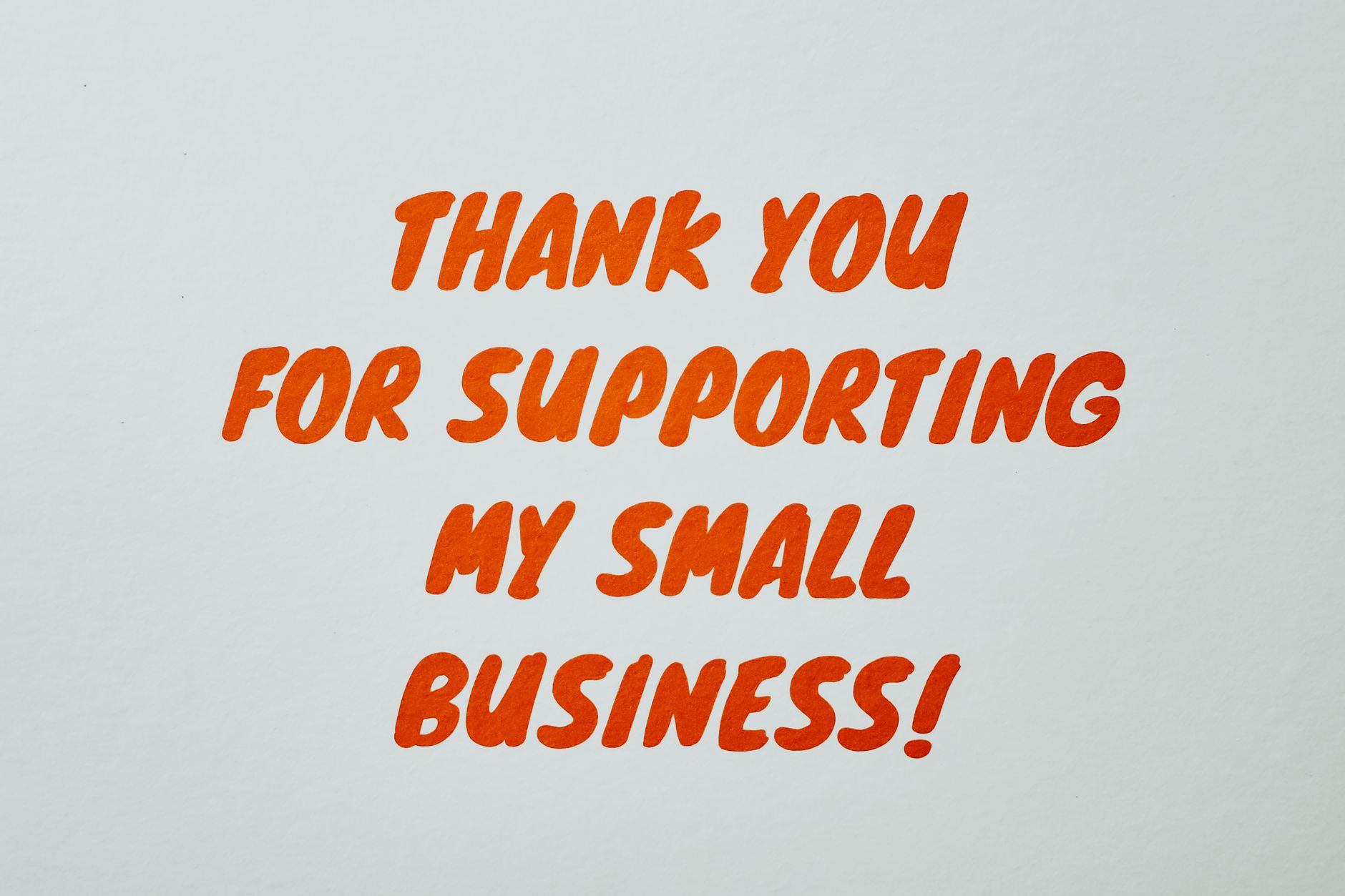 A small handwritten thank-you note tucked into a wrapped clothing parcel, a personal touch that turns a buyer into a repeat customer.