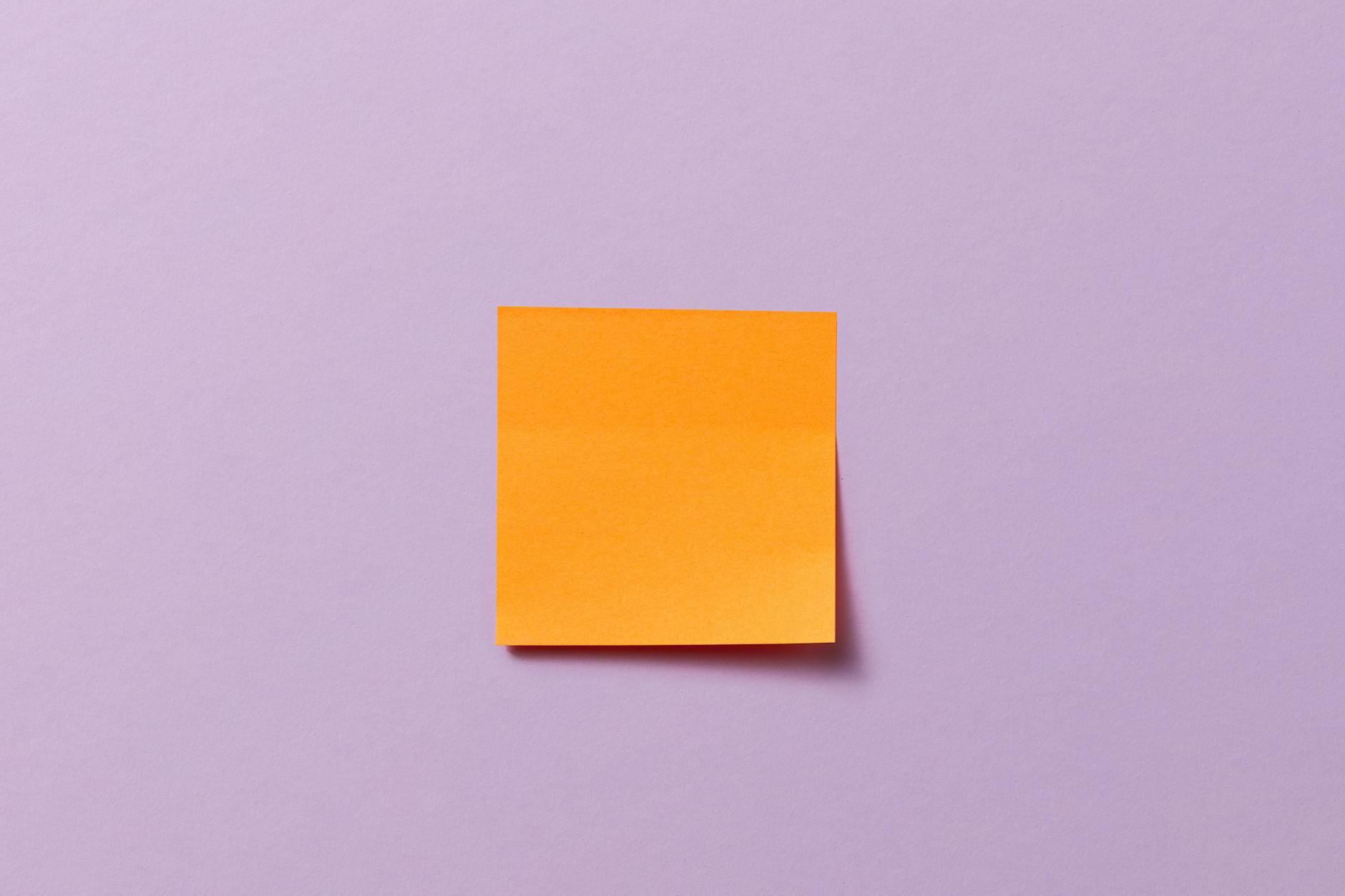 Orange sticky note centered on a pastel purple background, perfect for mockup and design uses.