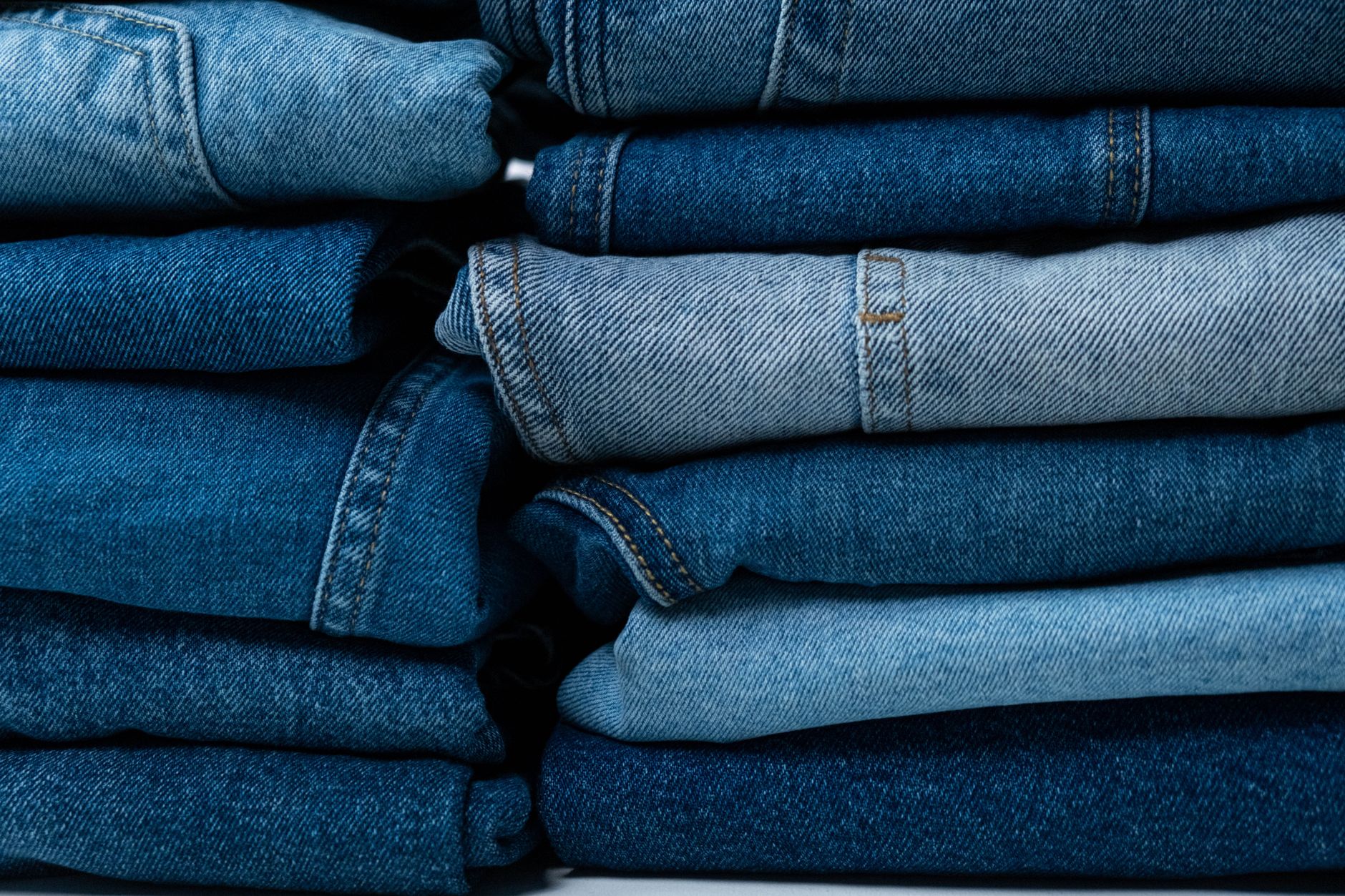 A tidy stack of folded secondhand clothes in coordinating colours sits on a table, grouped together ready to sell as a bundle.