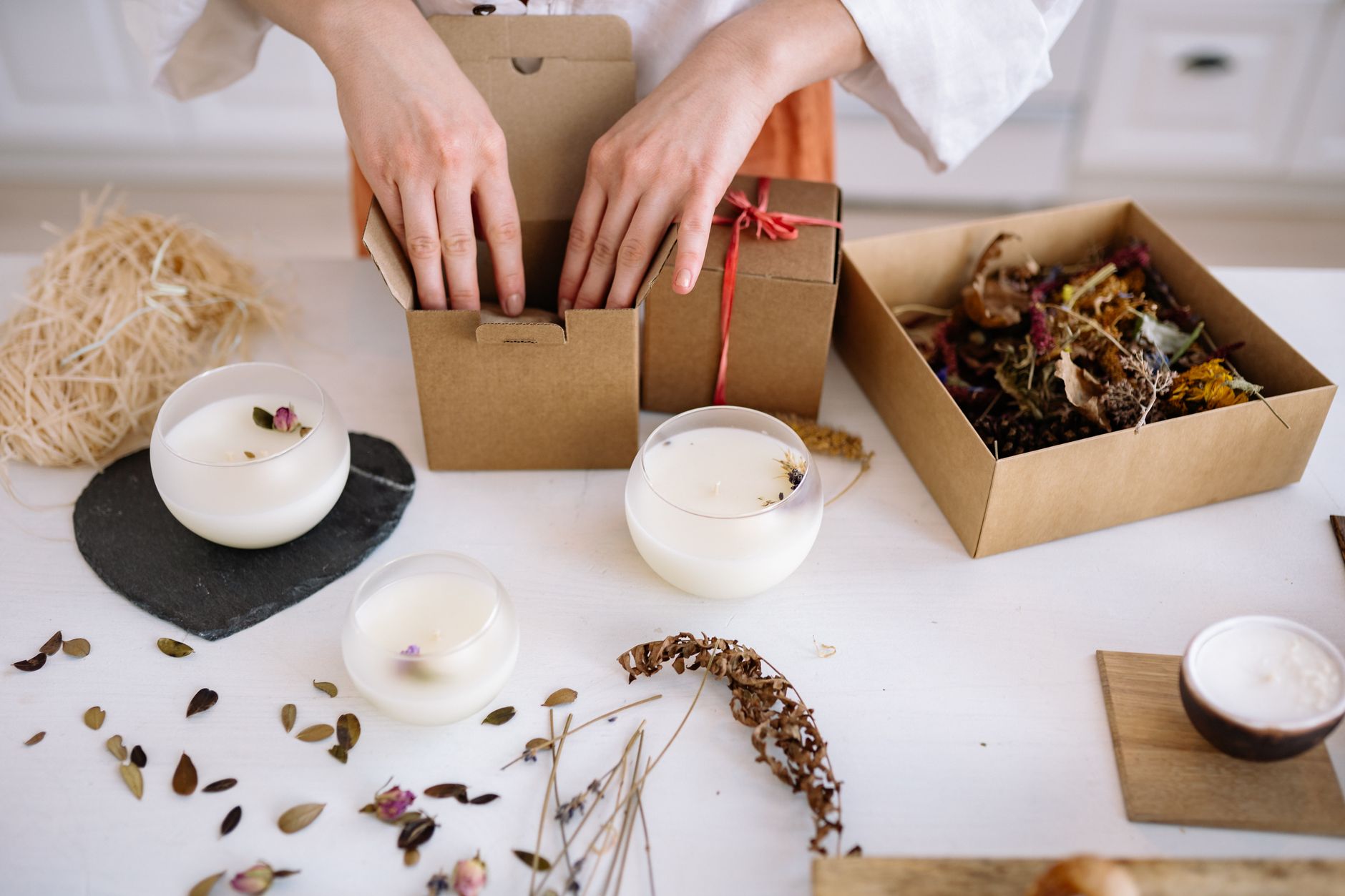 A maker packing handmade products into boxes at a table at home