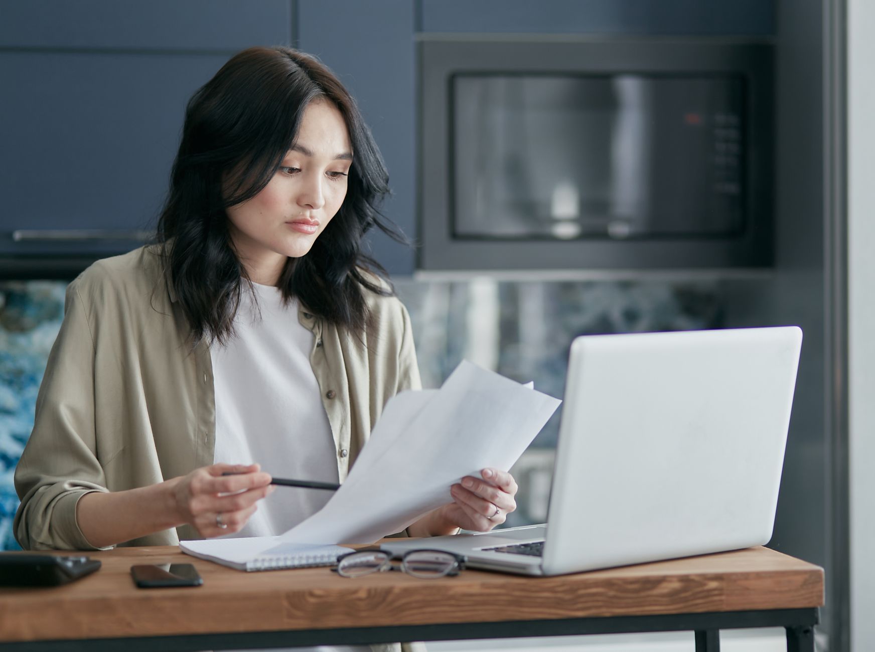 A person reading through paperwork at a kitchen table while setting up a home business