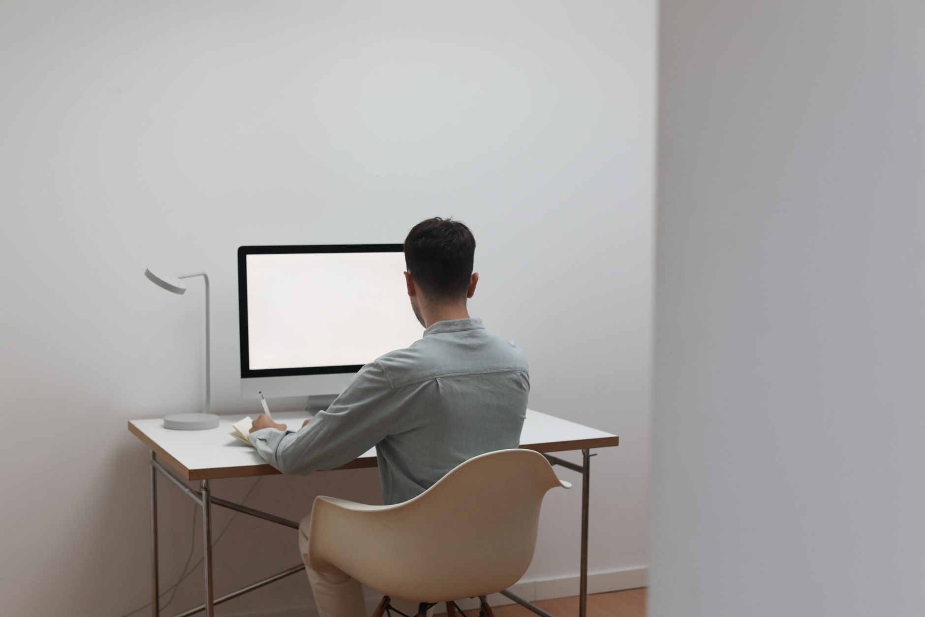 A person working at a simple home desk with a chair and a lamp, set up without overspending
