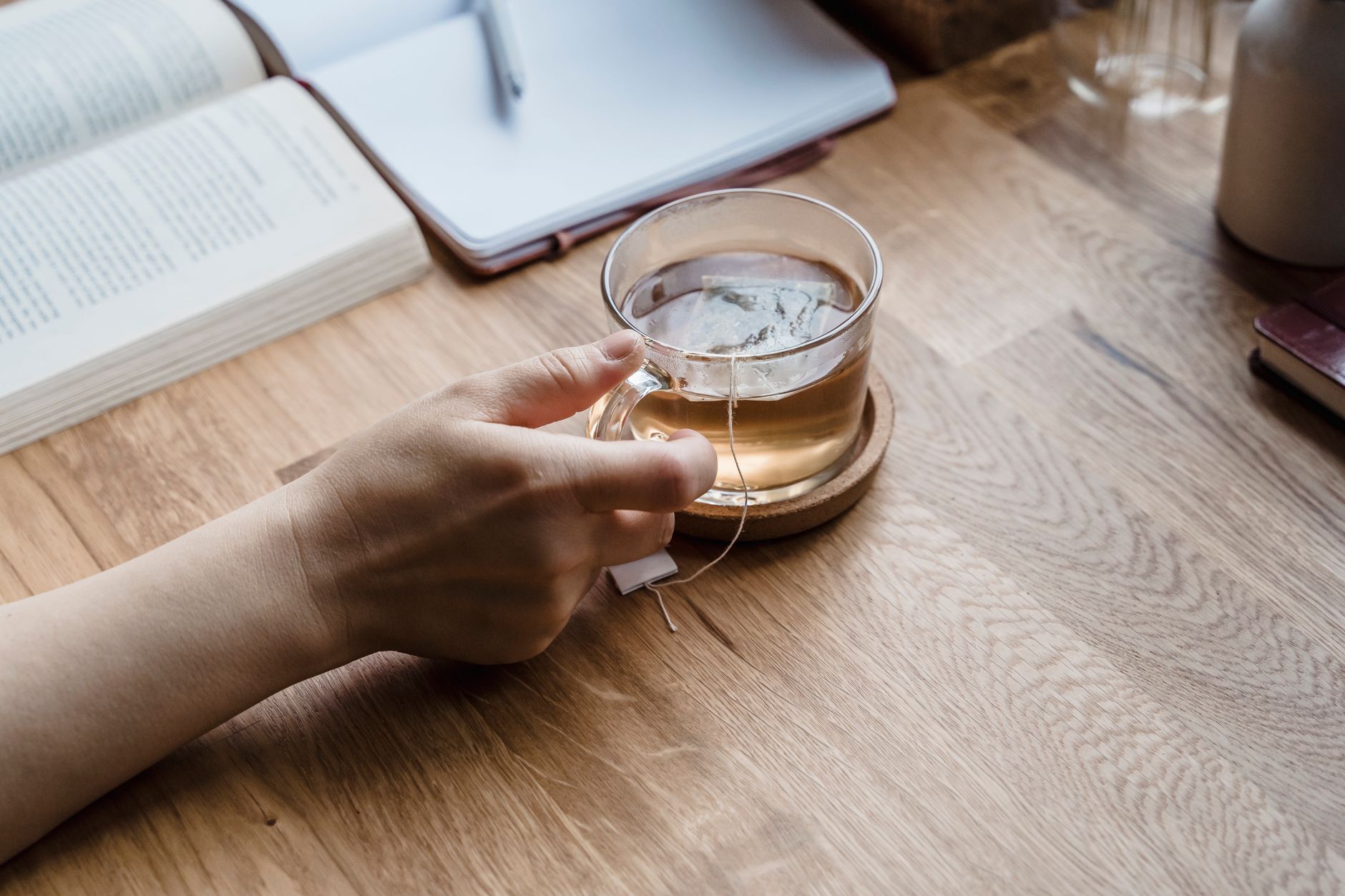 A person taking a short tea break by a window at home, reflecting on home business mistakes