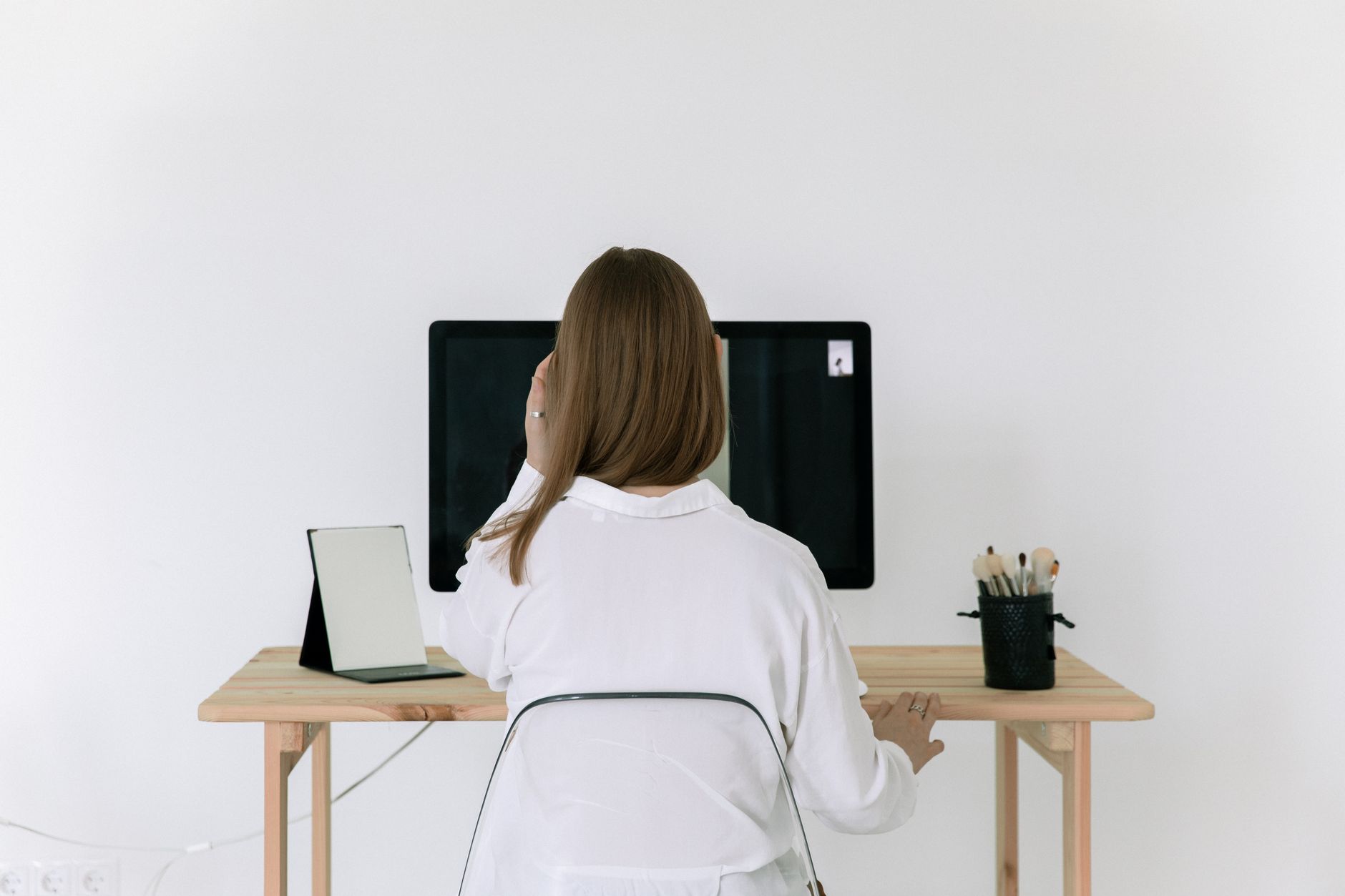 A woman working at a tidy desk in a bright corner of her home, running a business