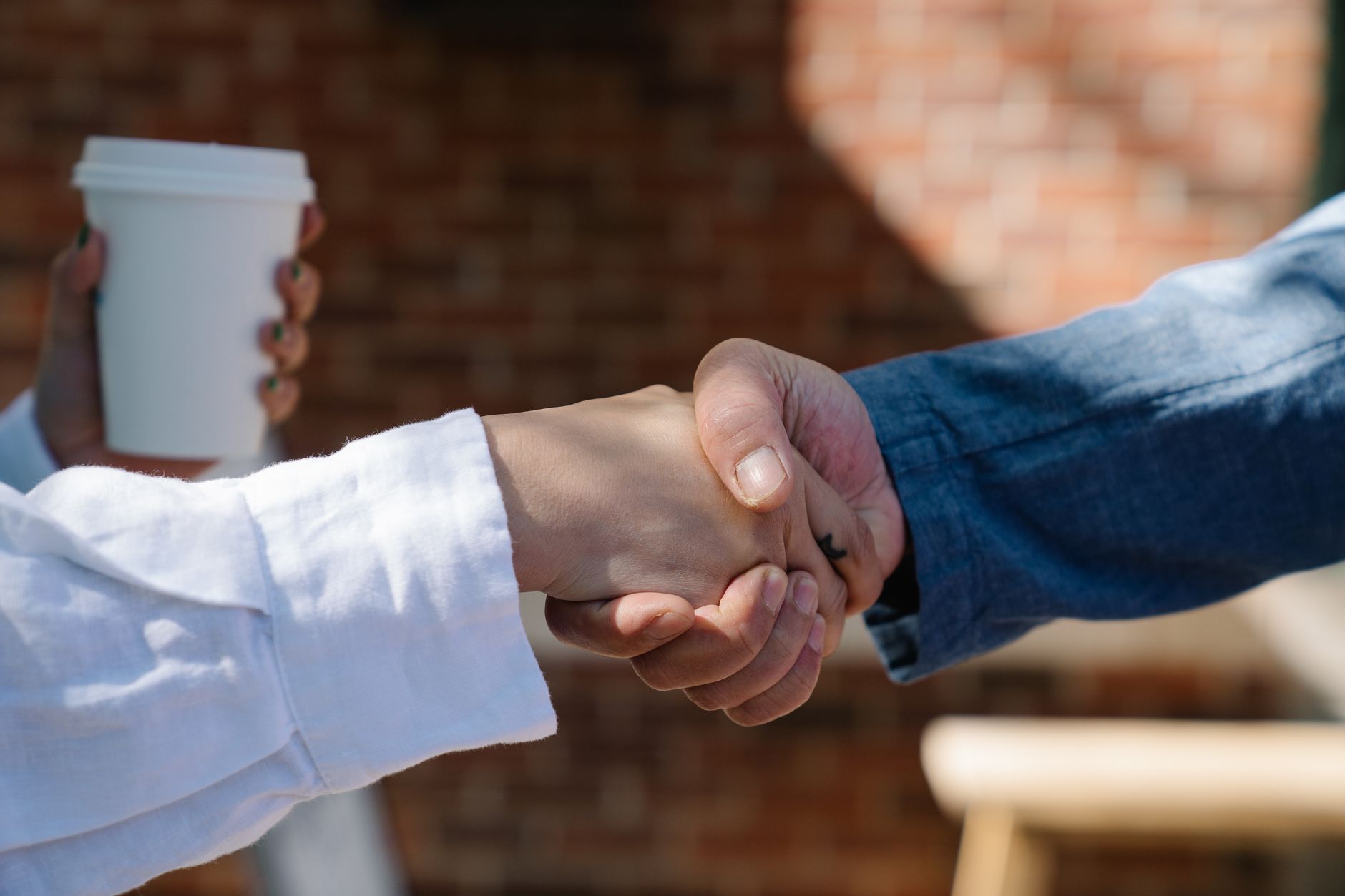 A person shaking hands with their first paying customer outside a home