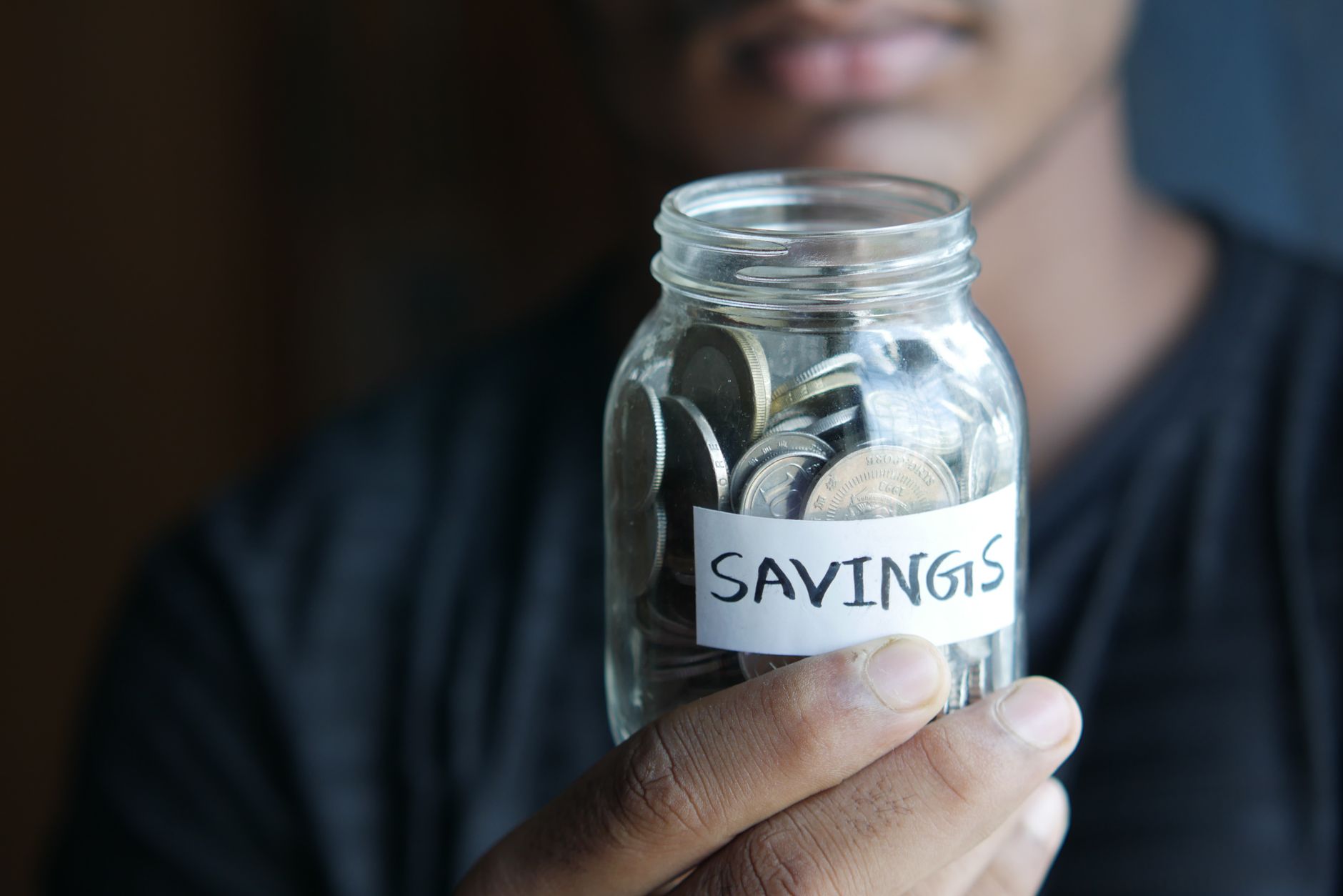 A person putting coins into a jar, reinvesting early profits rather than borrowing