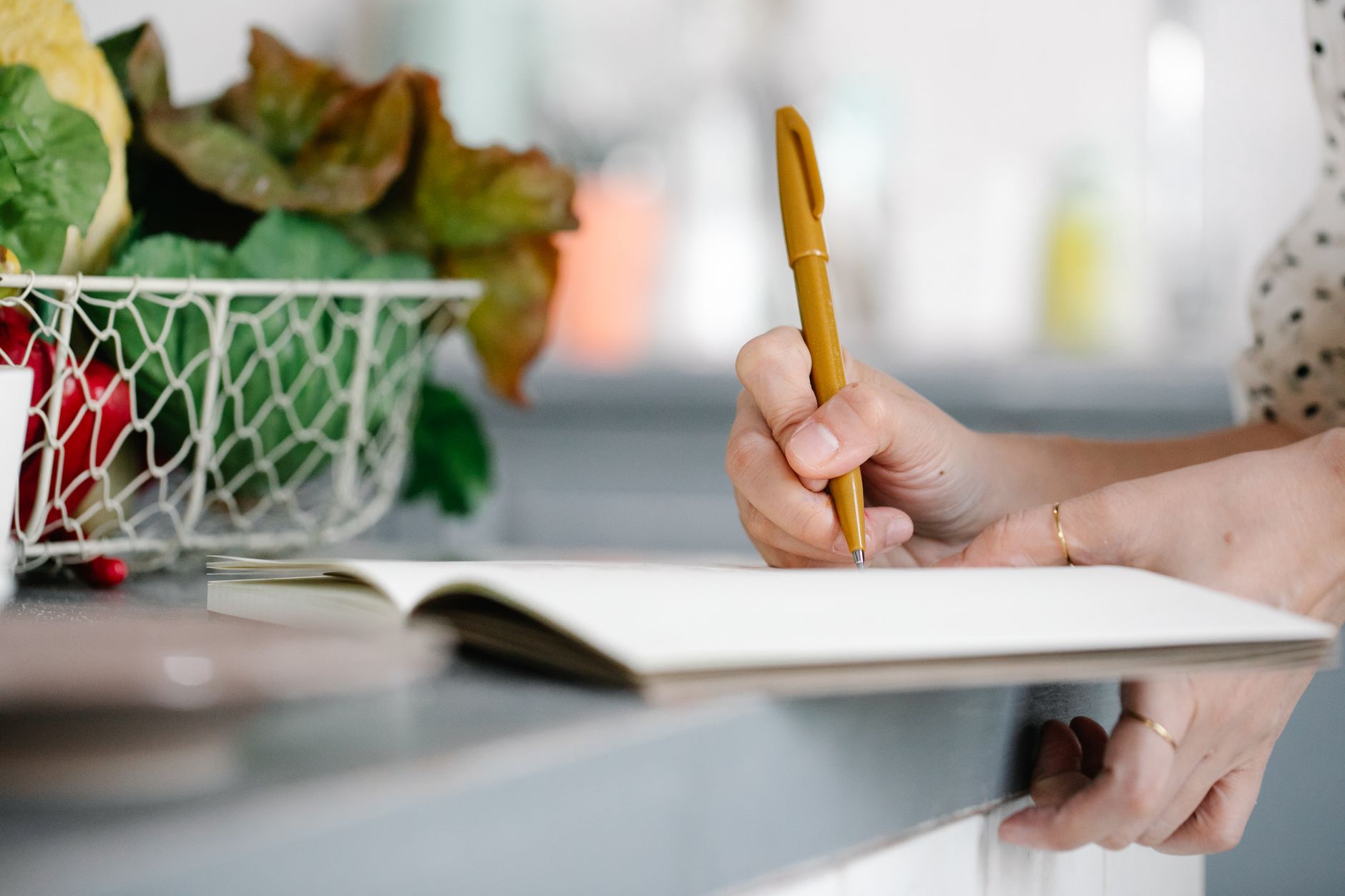 A person writing business plans in a notebook at a kitchen table, starting with almost nothing