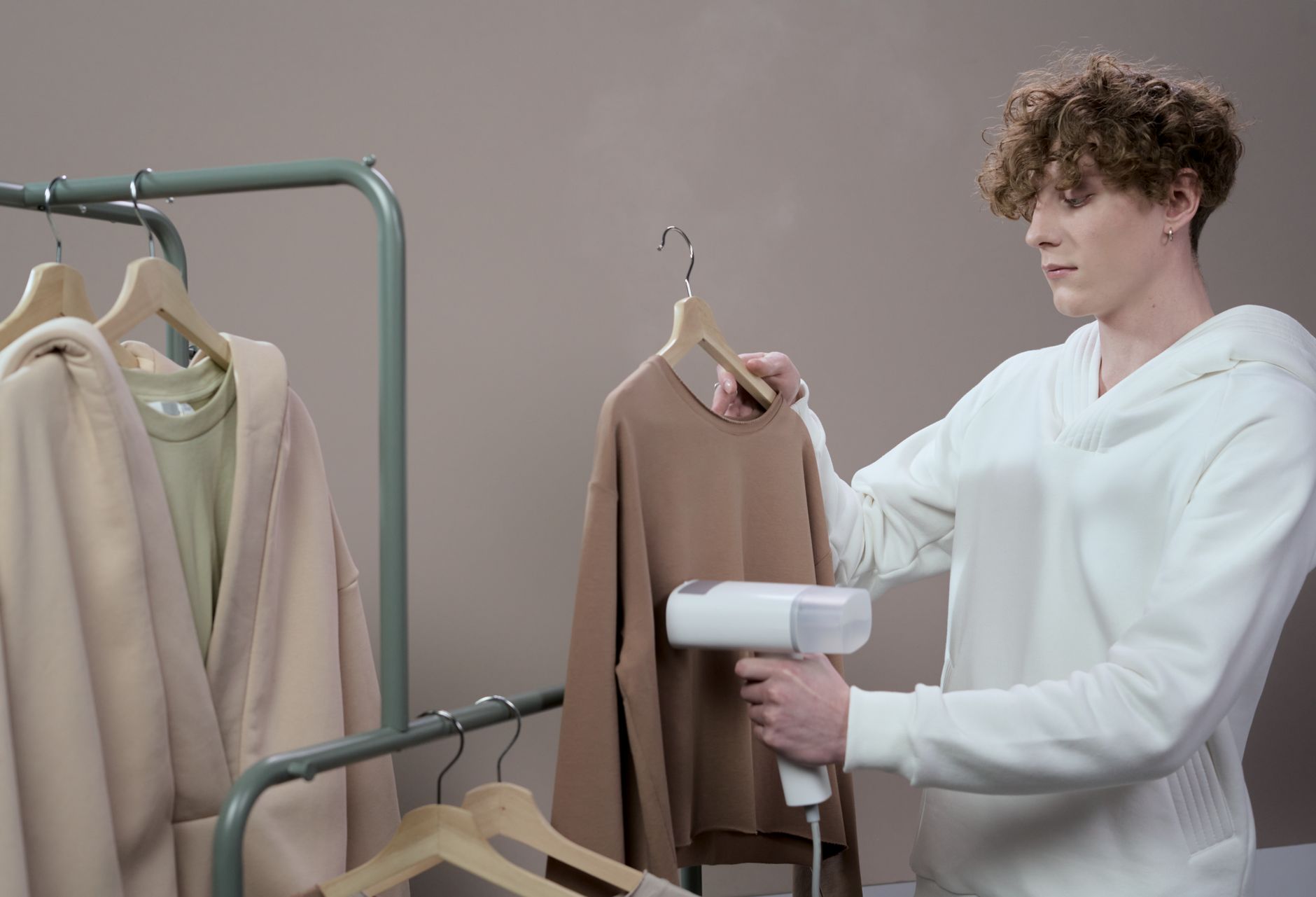 A person steaming and styling clothing on a table, preparing pieces to sell