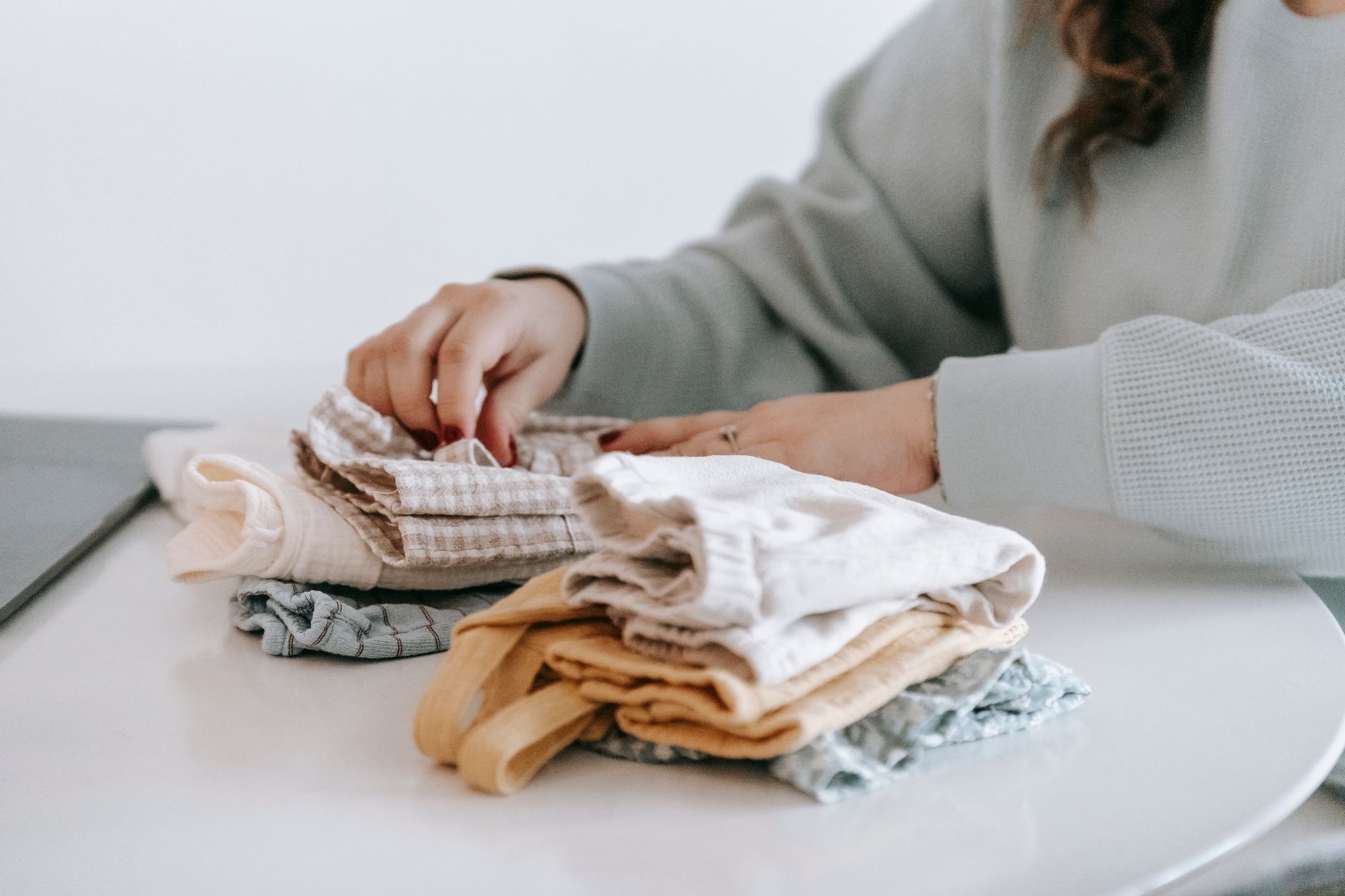 A person photographing folded clothing at a table to share on social media and find customers