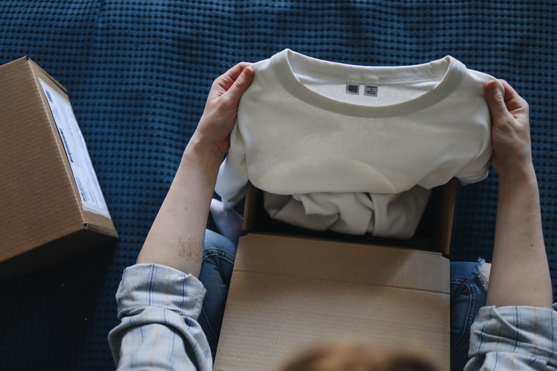 A person standing among boxes of unsold folded t shirts, a common mistake of over ordering stock