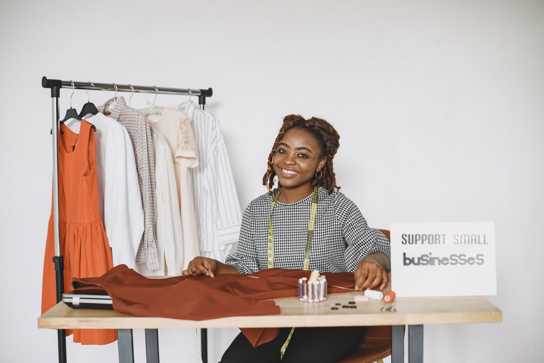 A clothing brand owner sorting garments on a rail in a bright studio