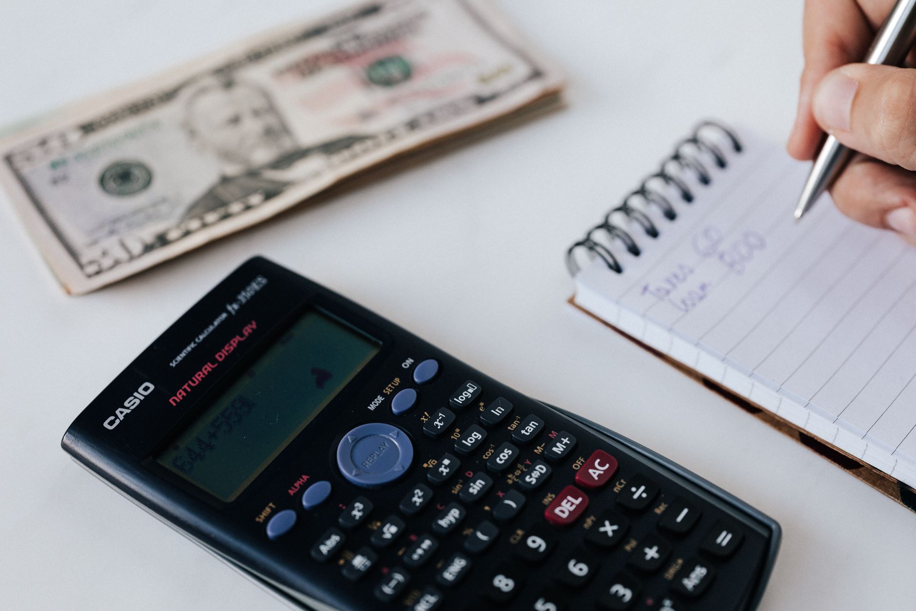 Hands using a calculator beside a notebook while working out fair dog walking prices