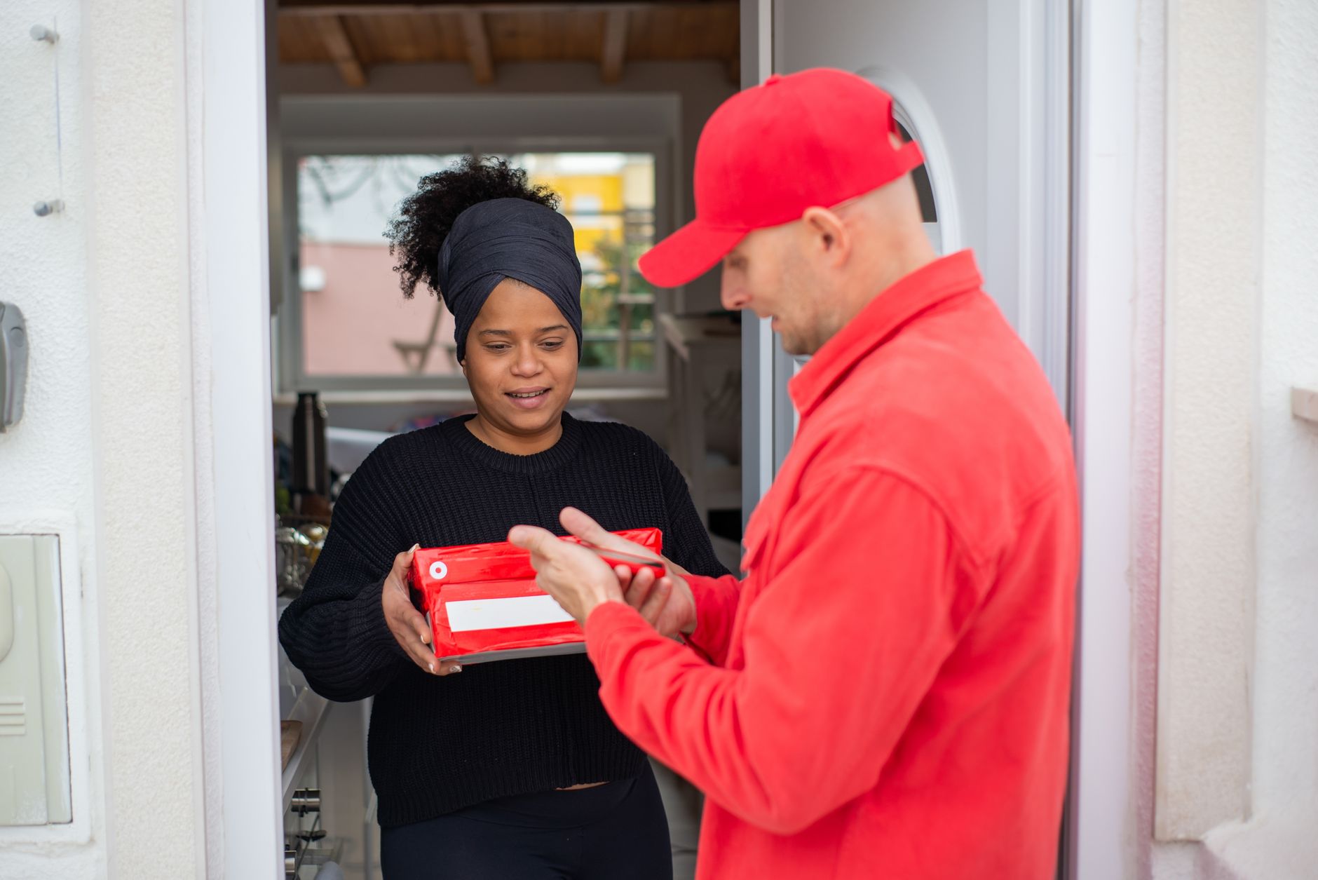 A courier handing a parcel to a woman at her front door