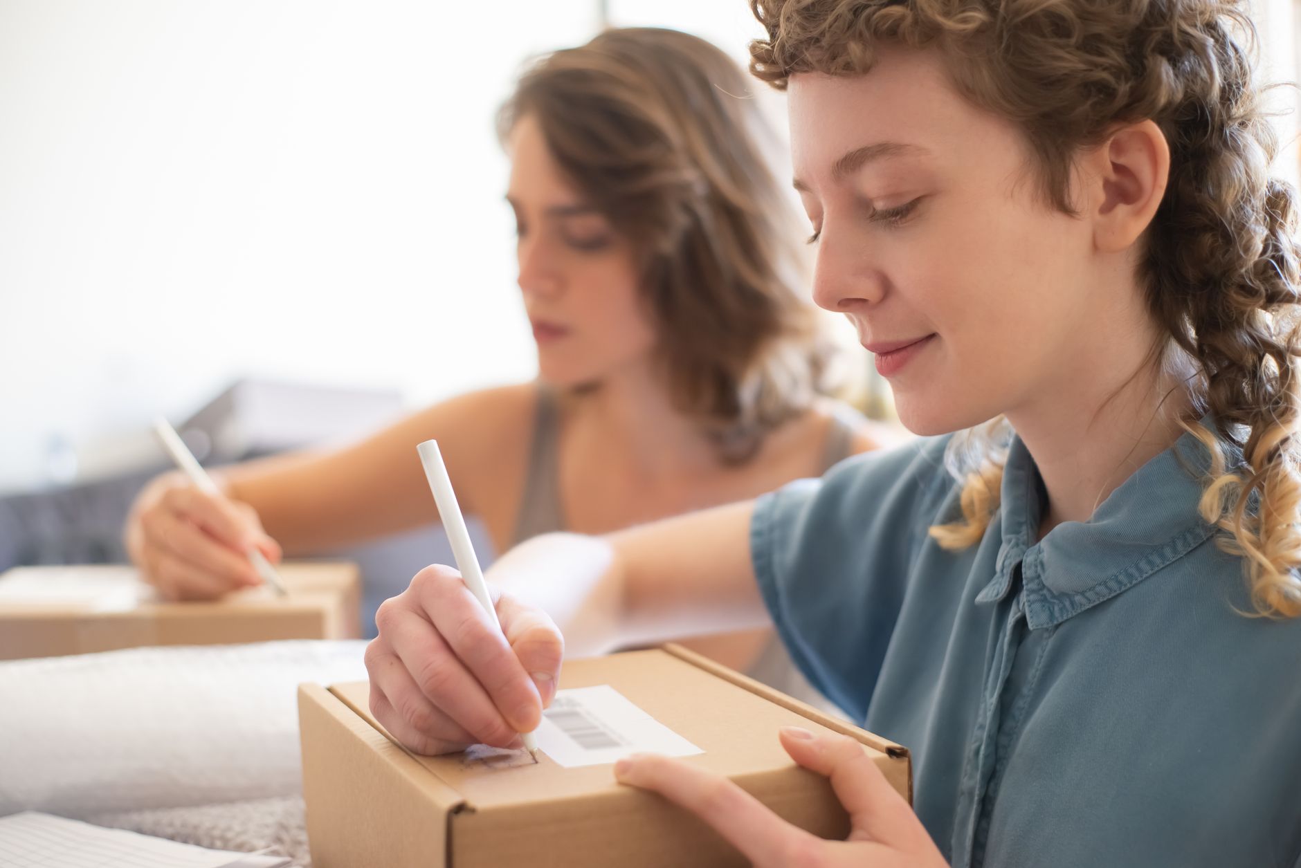 A small online shop owner packing customer parcels at a table at home