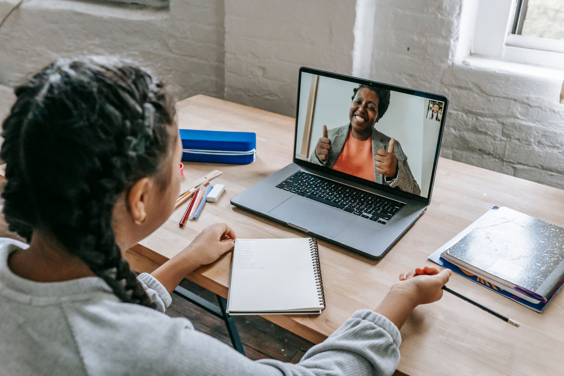 A tutor wearing a headset delivers an online lesson on a laptop, the screen showing a shared document during a video tutoring session.