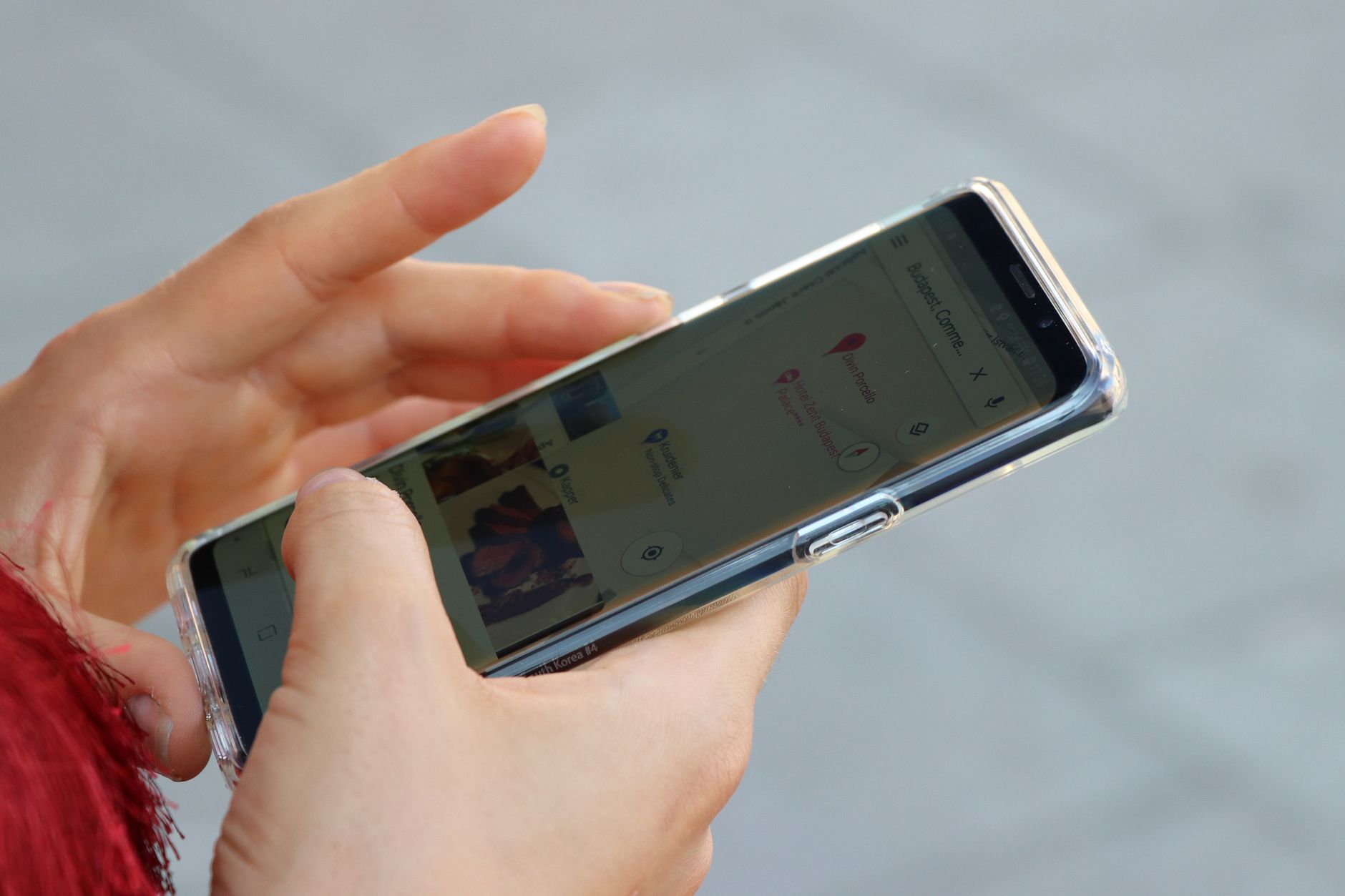 A parent holds a phone showing a local map search while looking for a nearby tutor for their child.