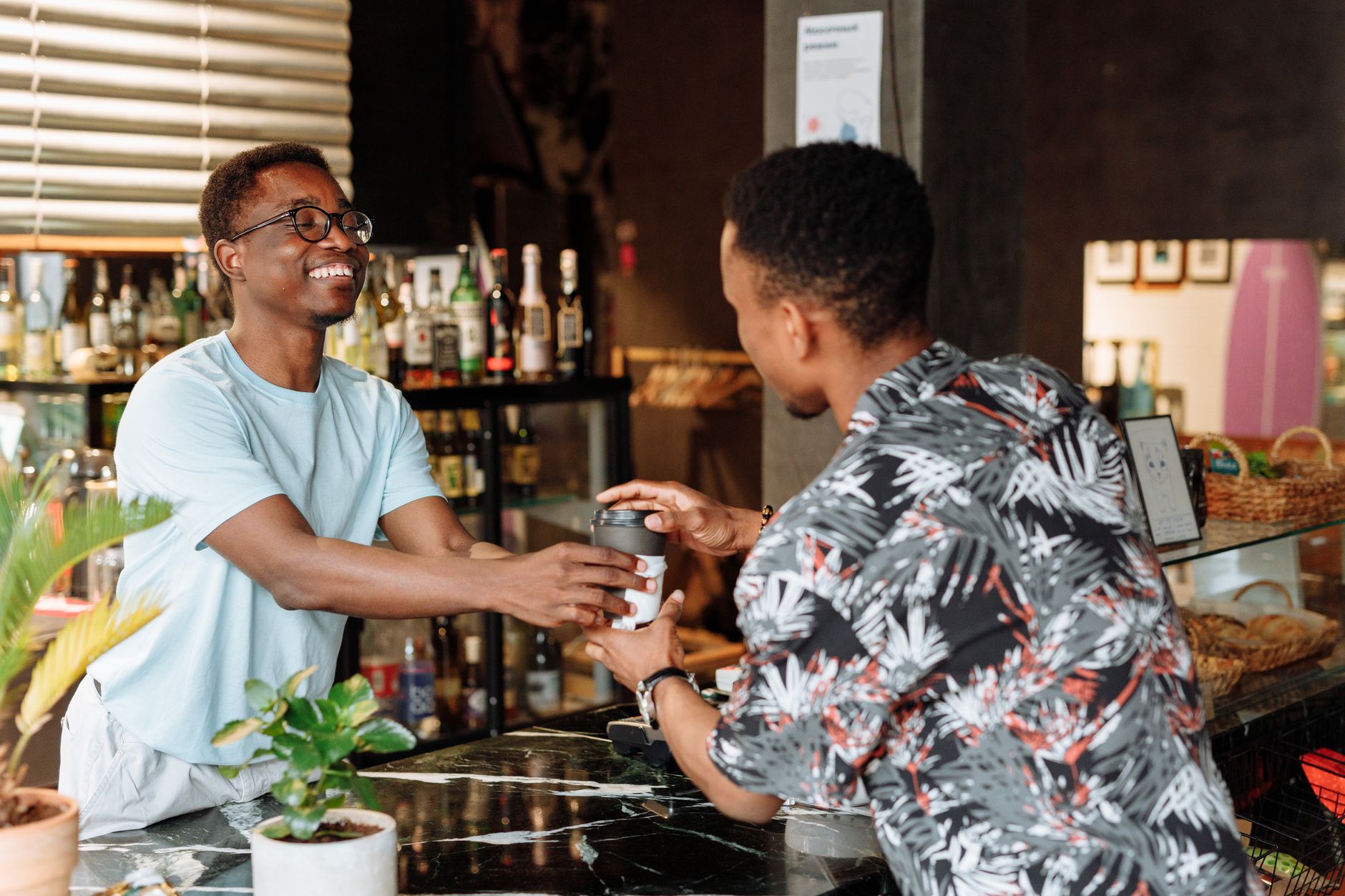 A cafe owner serving a customer with consistently branded cups