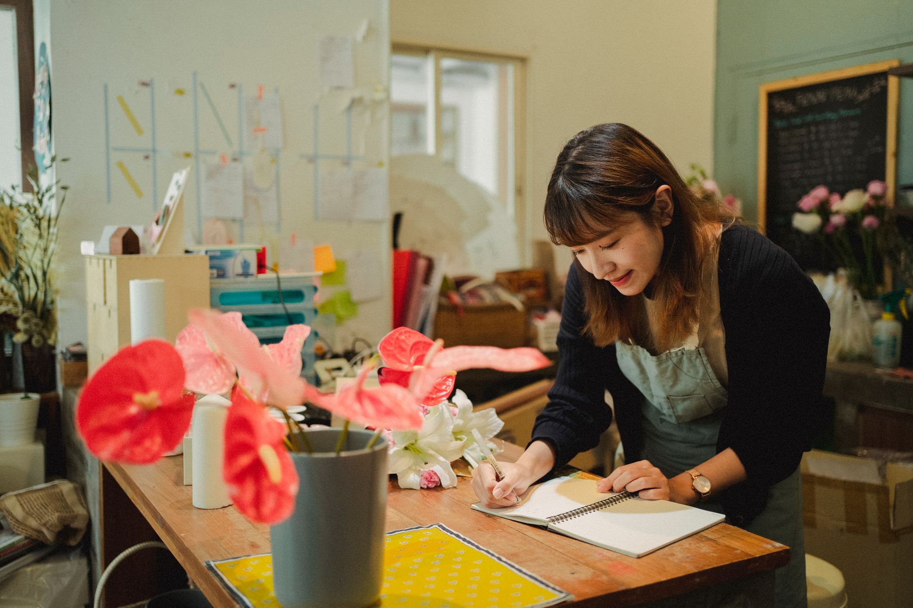 A florist planning her marketing dates in a diary at the counter