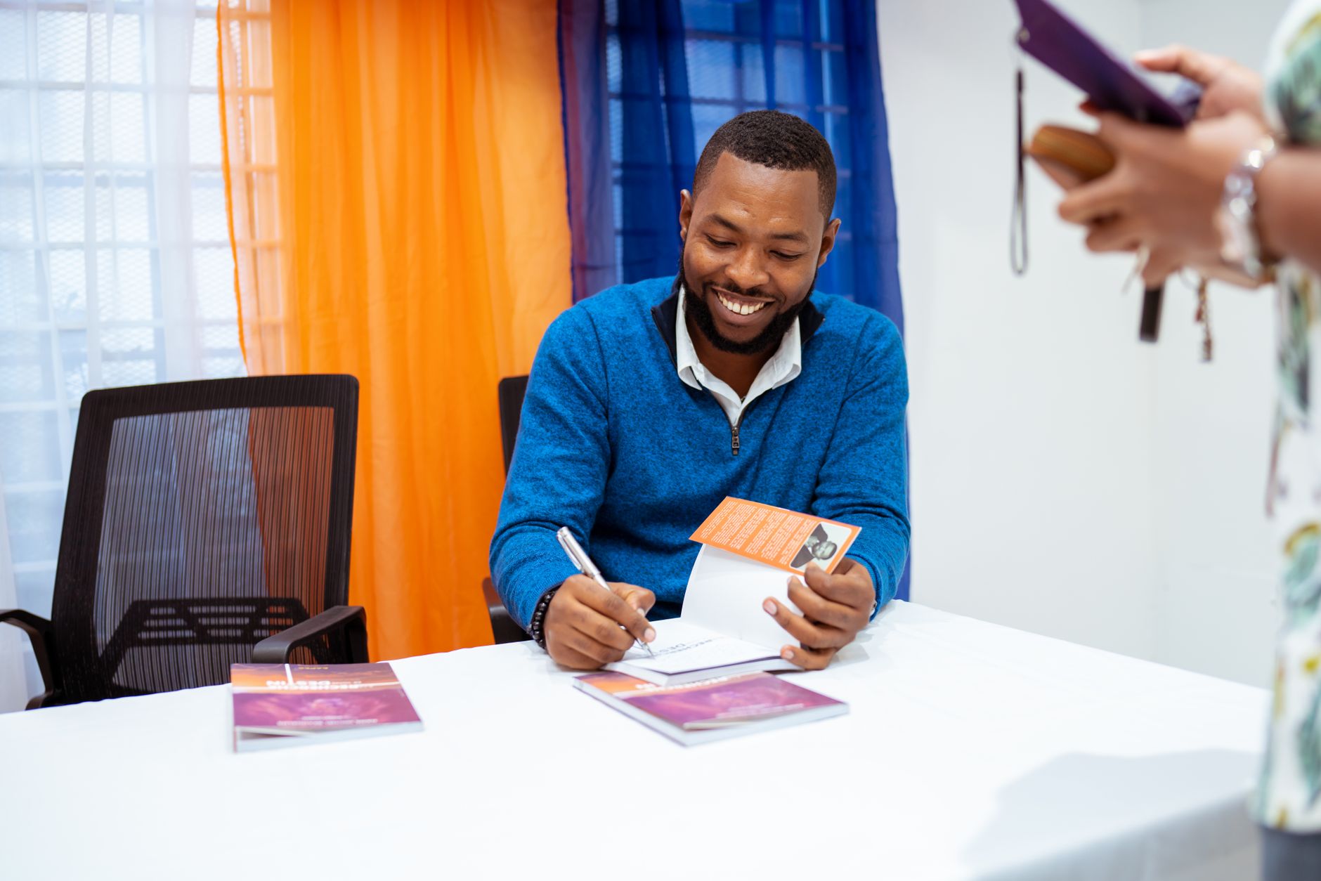 An author signing copies at a small book launch event