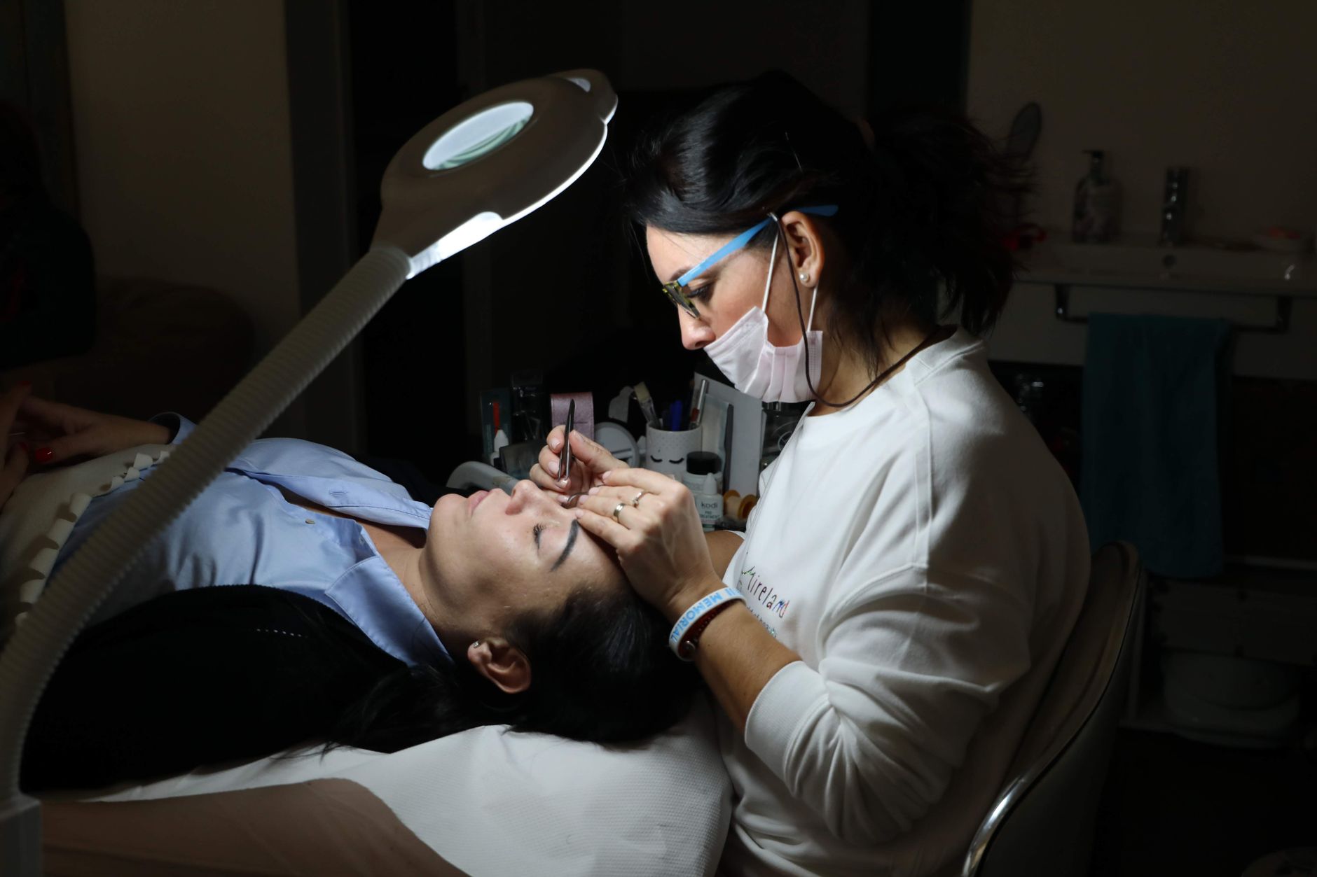 A beautician finishing a treatment for a client in her salon