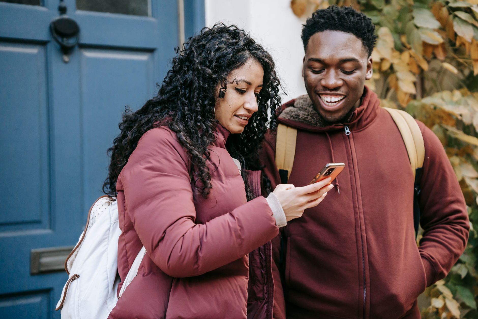 A couple checking booking details on a phone outside a guest house