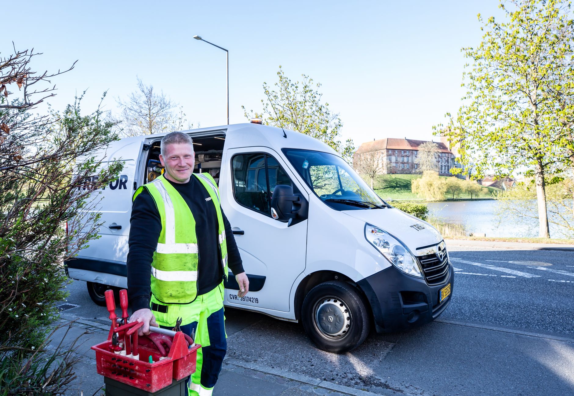 An electrician standing next to their branded work van outside a client's home