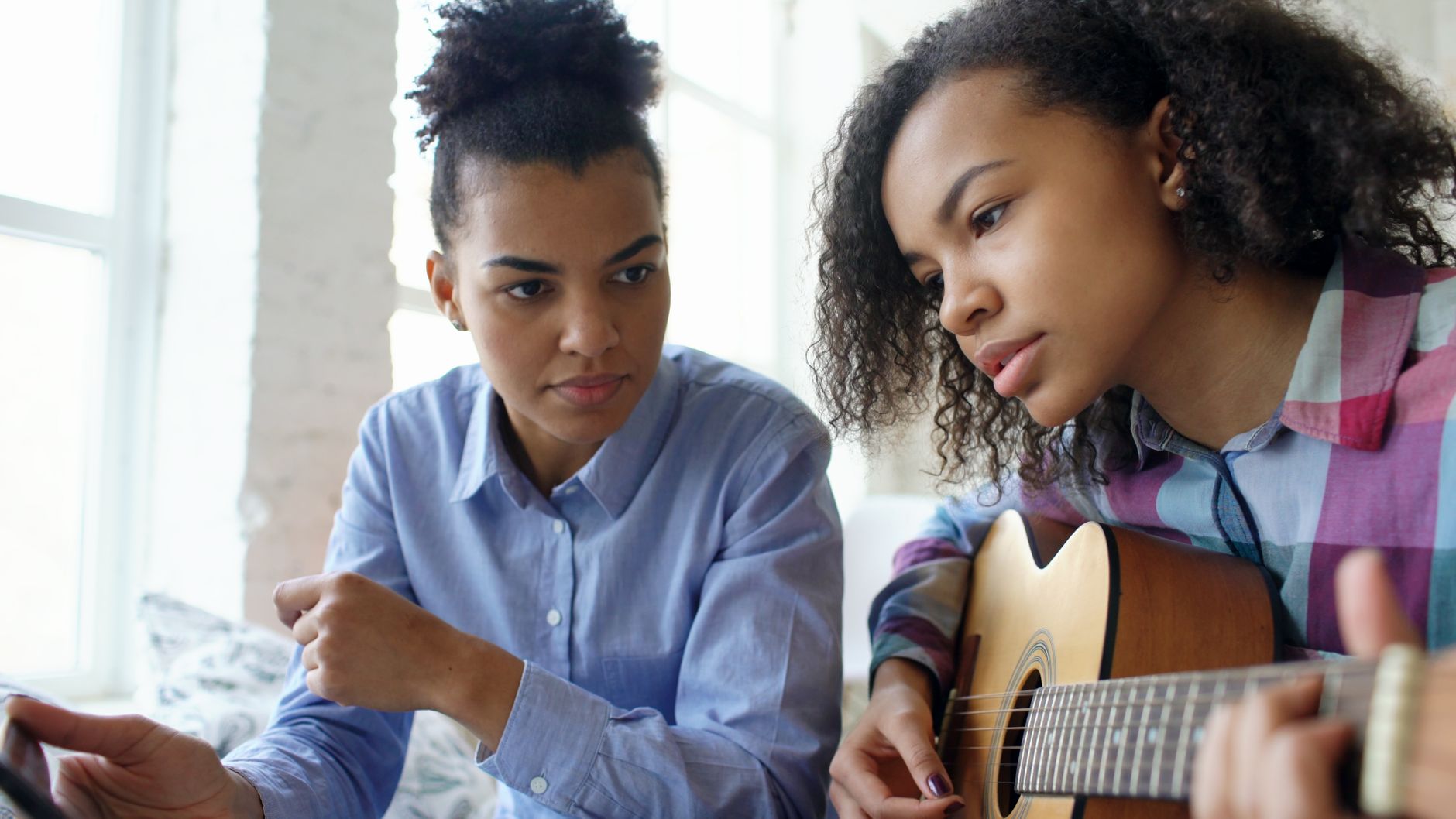 An adult beginner learning guitar with an encouraging teacher
