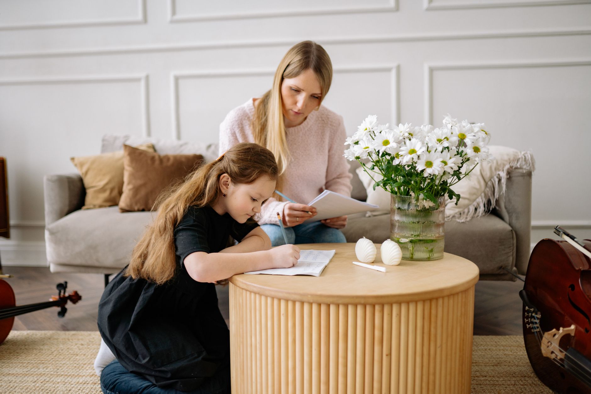 A parent checking reviews while their child practises violin