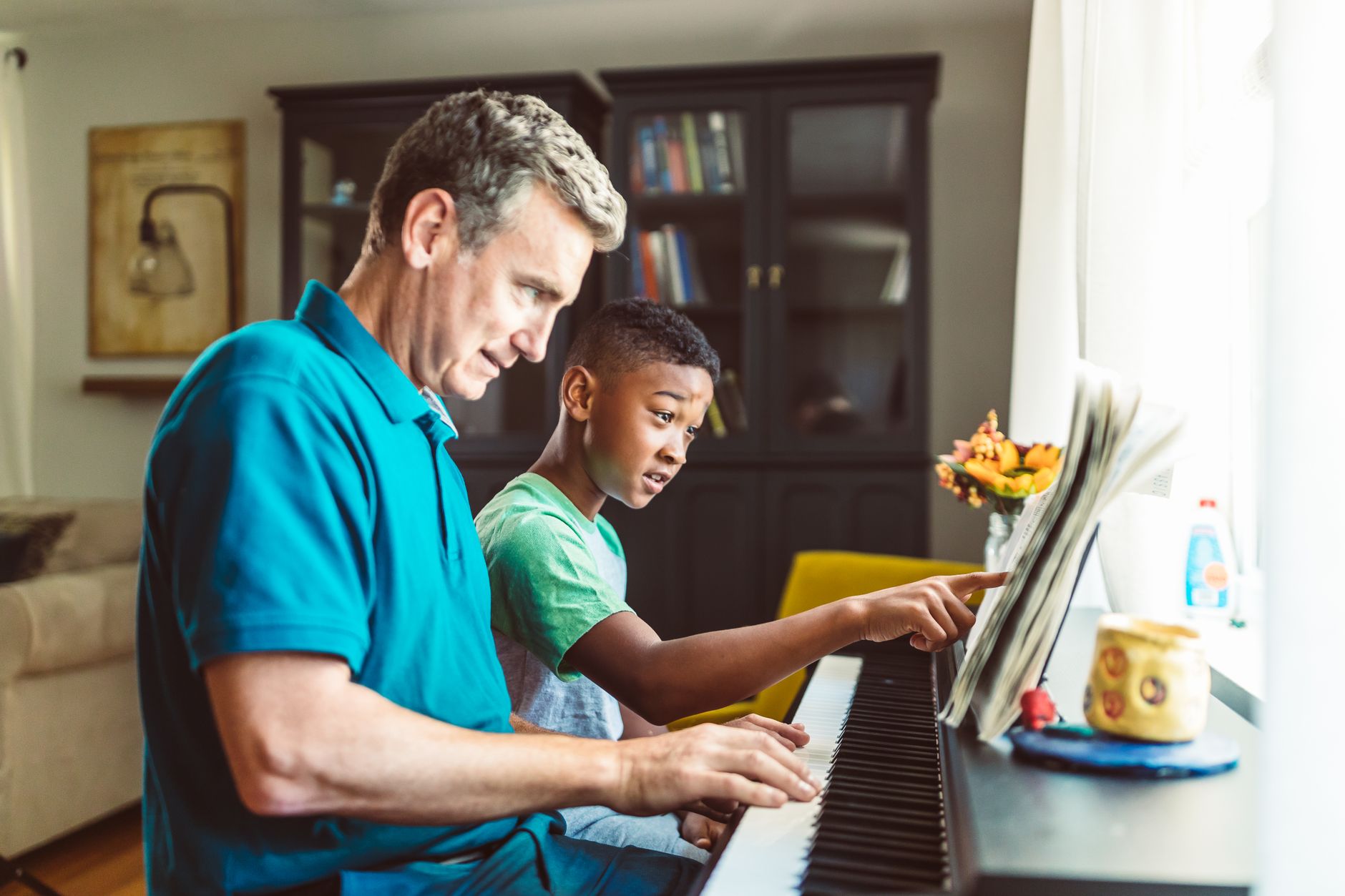A music teacher giving a piano lesson to a young student at home
