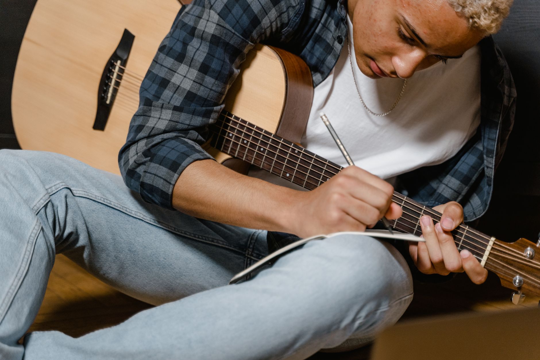 A singer-songwriter planning their next release with a notebook and guitar