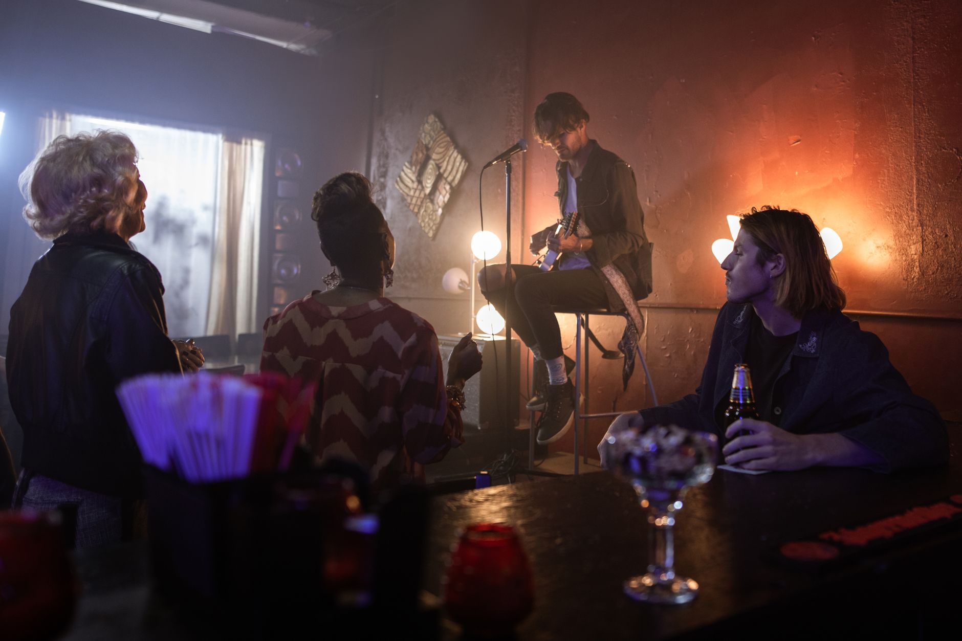 A folk singer performing to a small, engaged audience in an intimate room