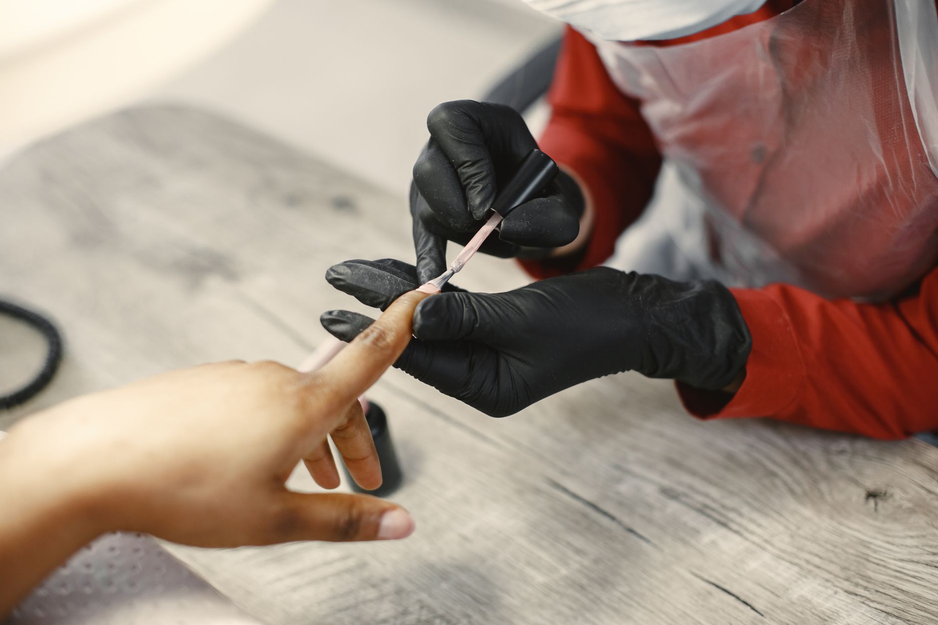 A nail technician giving a client a gel manicure in a small studio