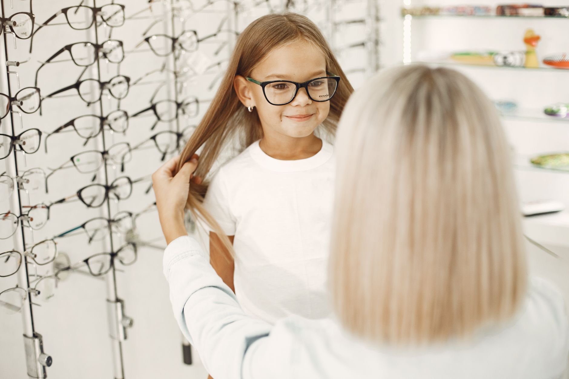 An optician carefully fitting a child's first pair of glasses