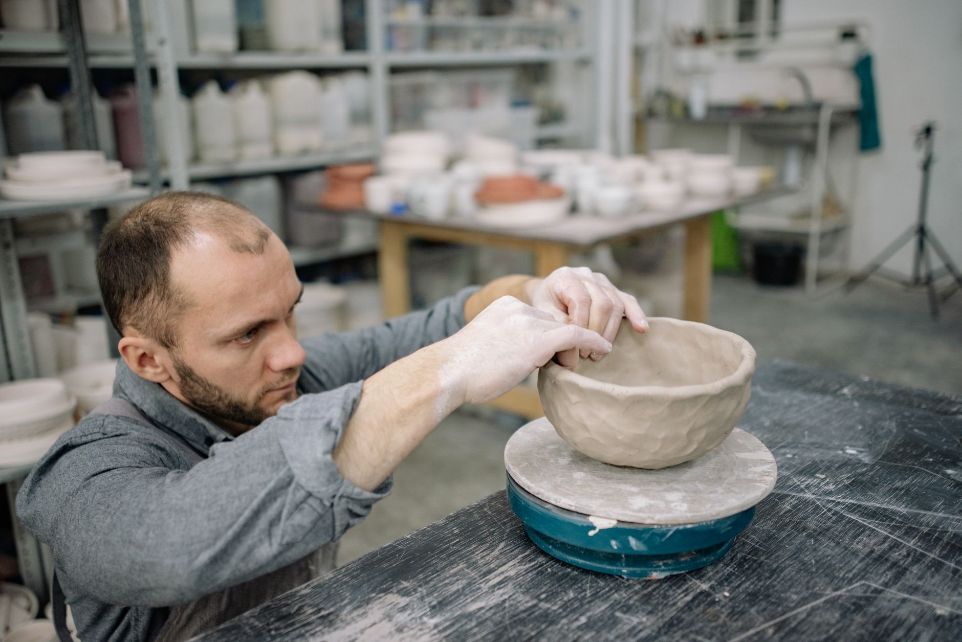 A potter shaping a bowl at the wheel in their workshop