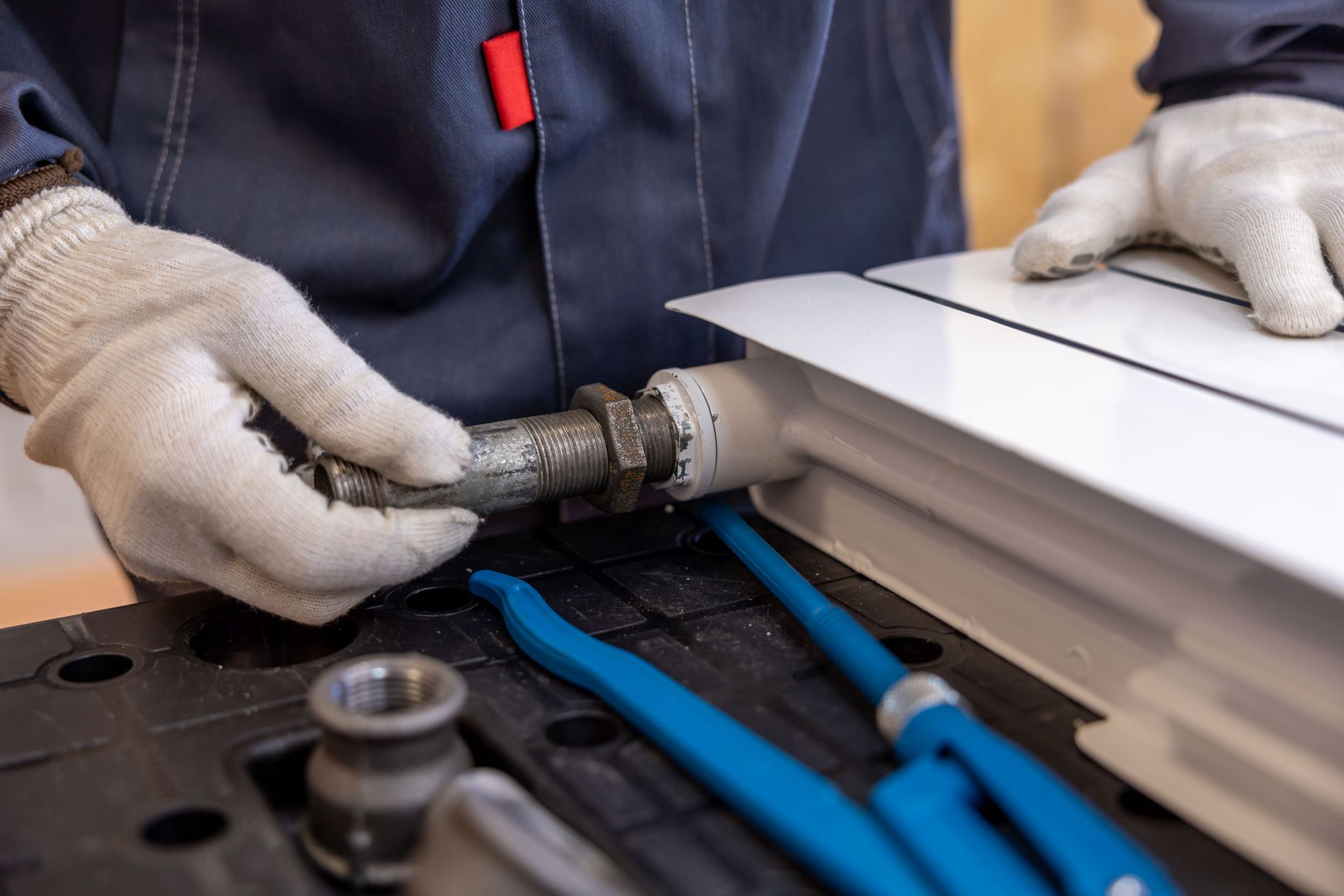A plumber repairing a leaking pipe under a kitchen sink