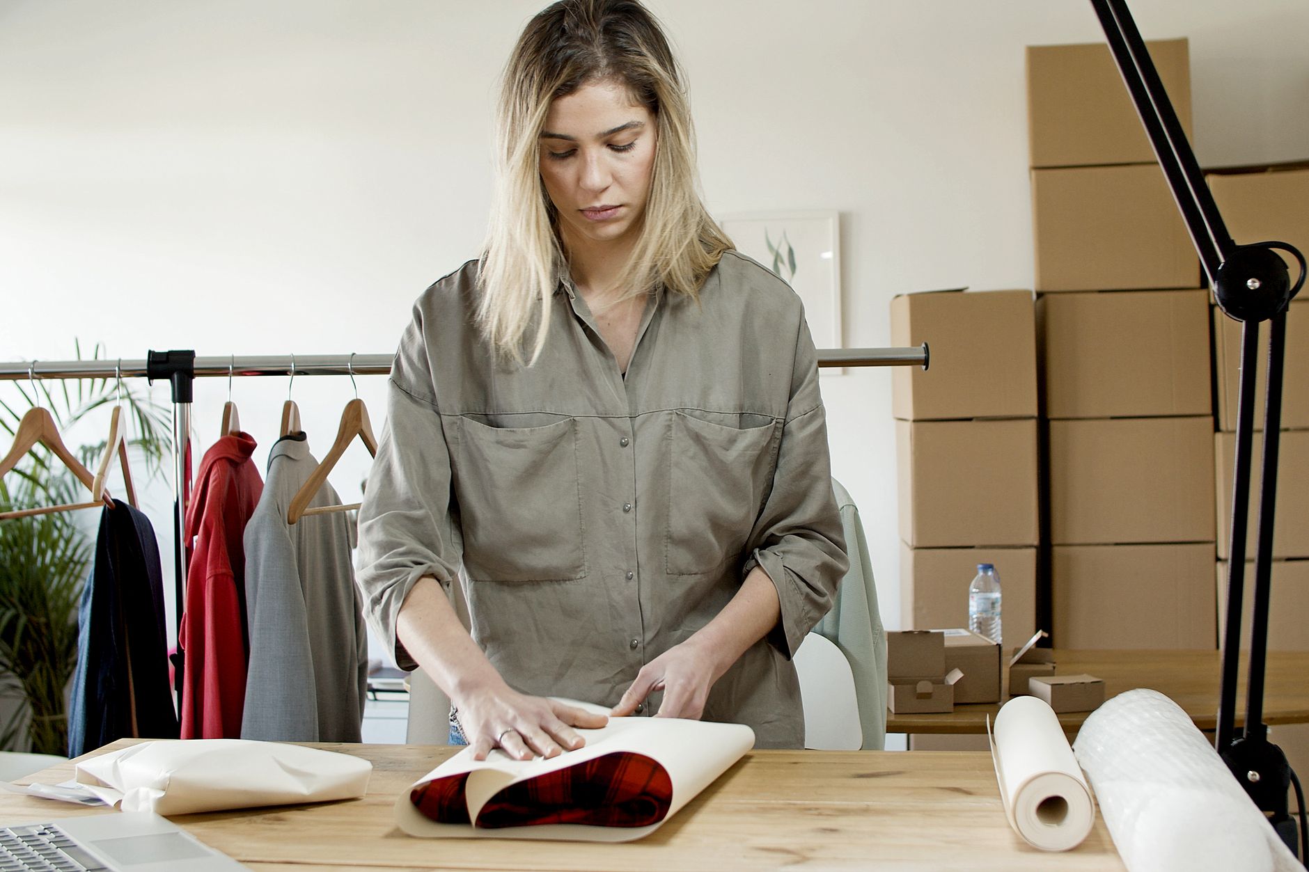 A small shop owner packing homeware orders into boxes at a table