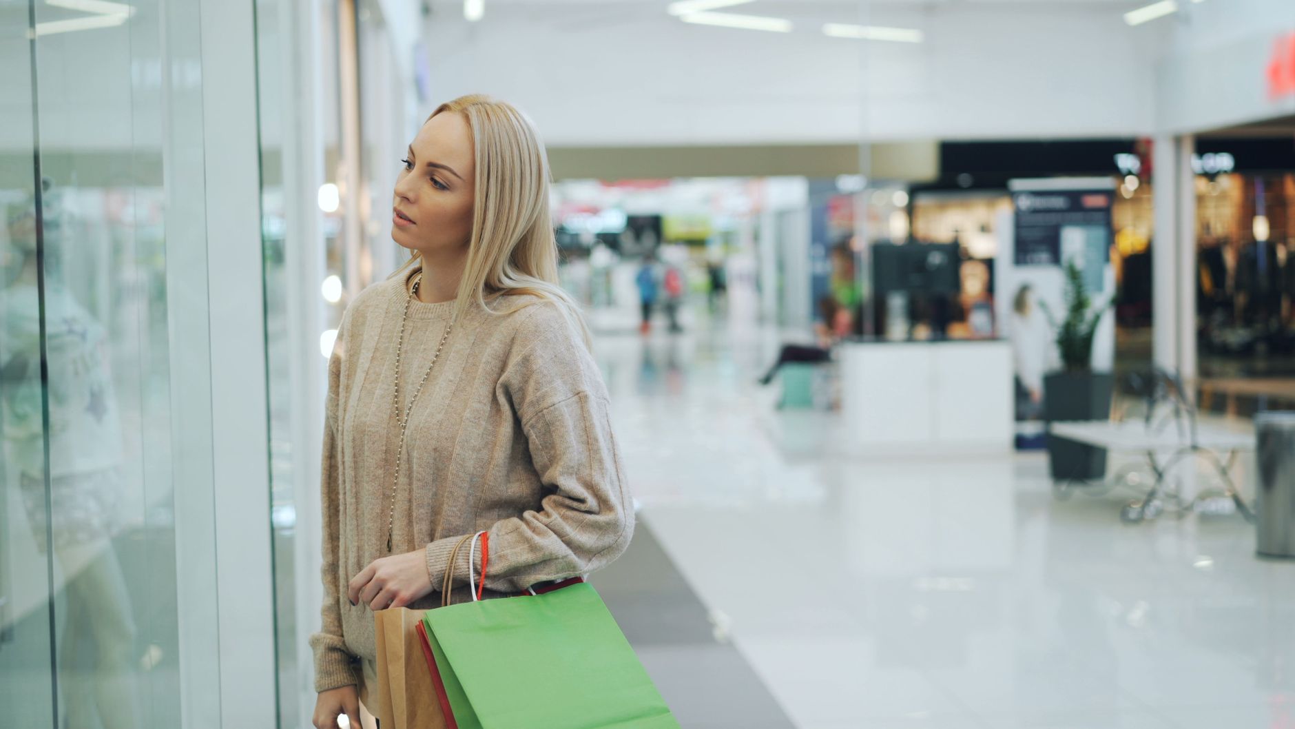 A shopper pausing outside a shop window to consider buying