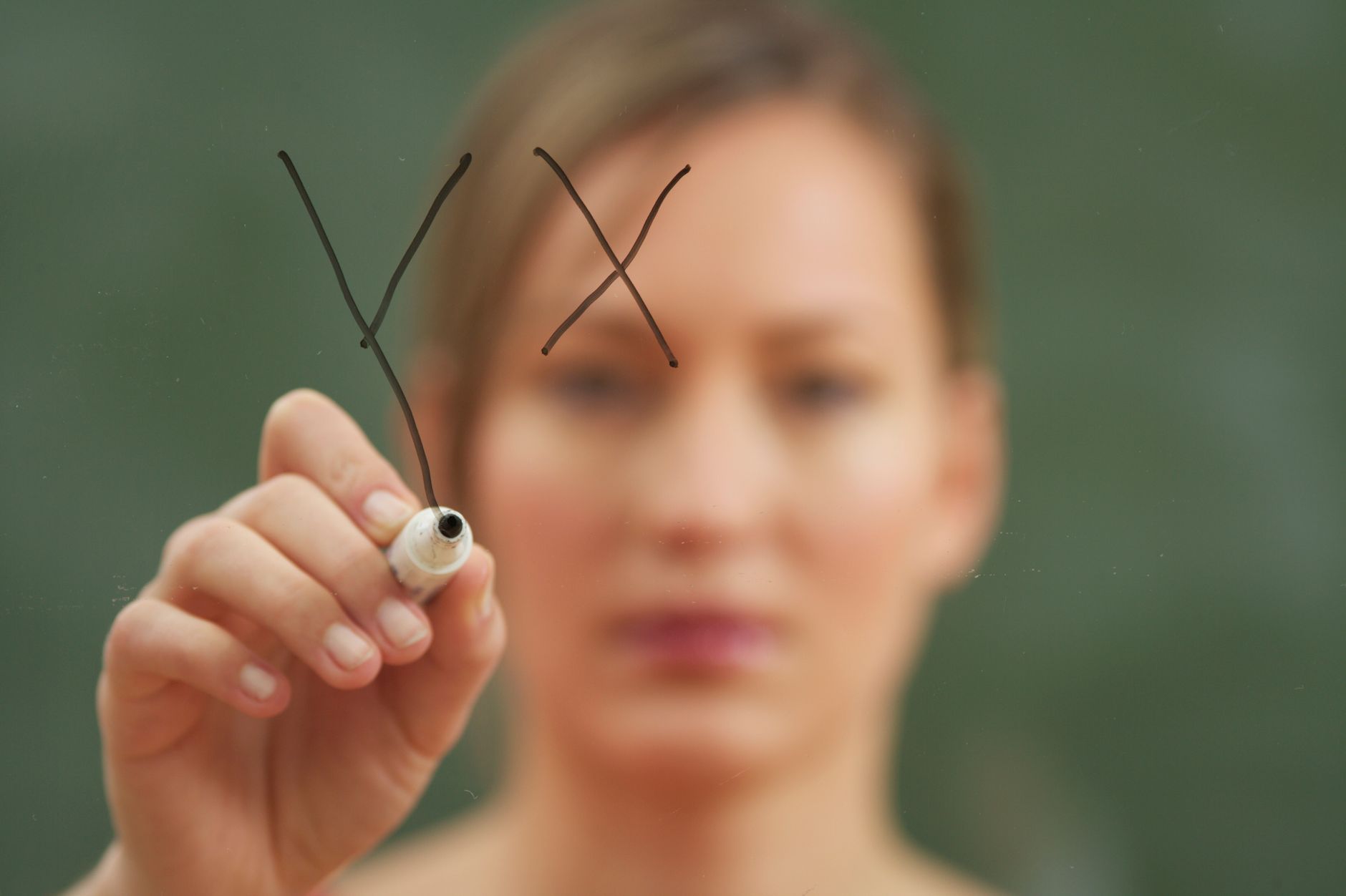 A woman mapping out steps on a glass wall with a marker