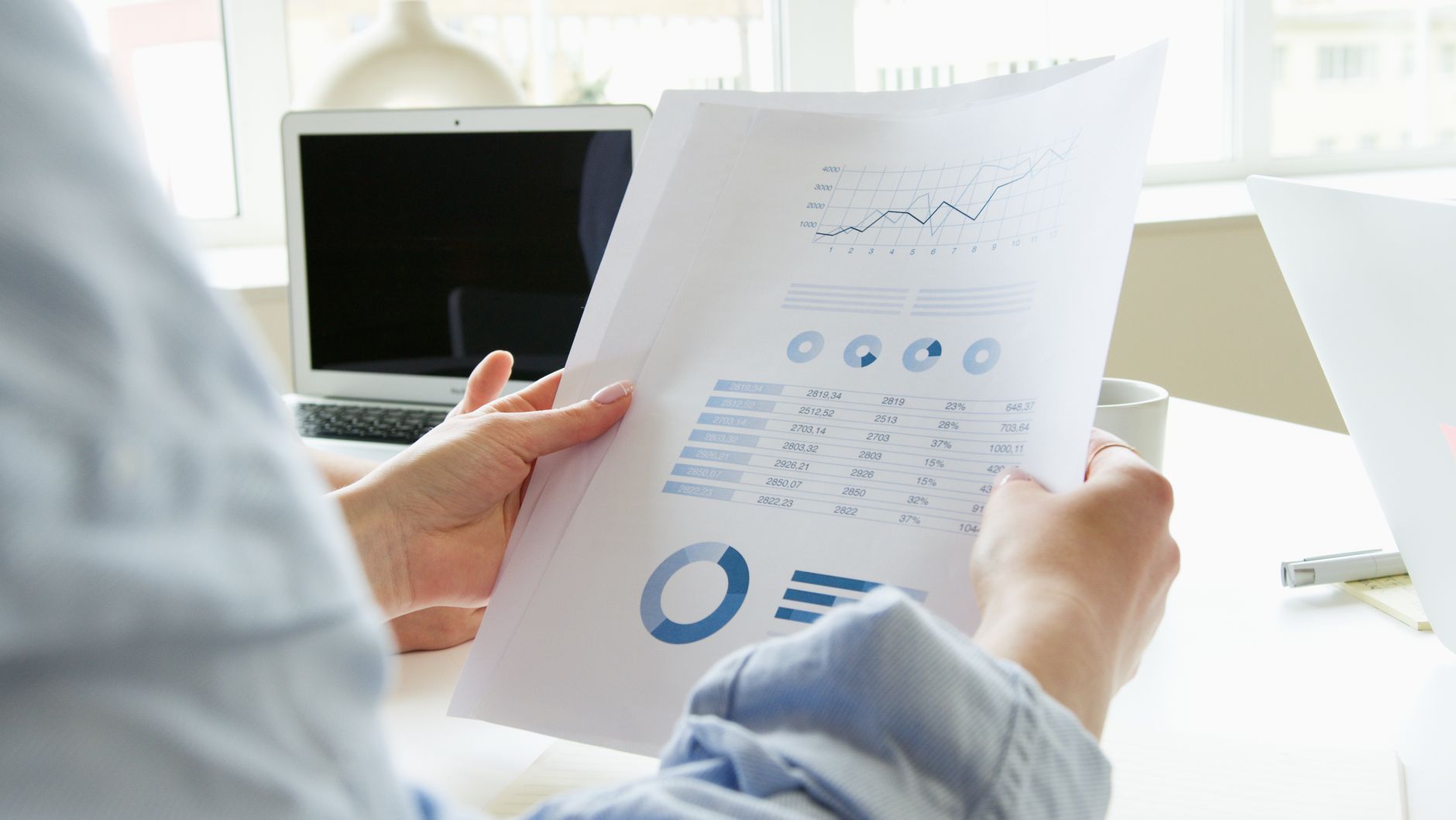 Two people reviewing printed business reports together at a desk