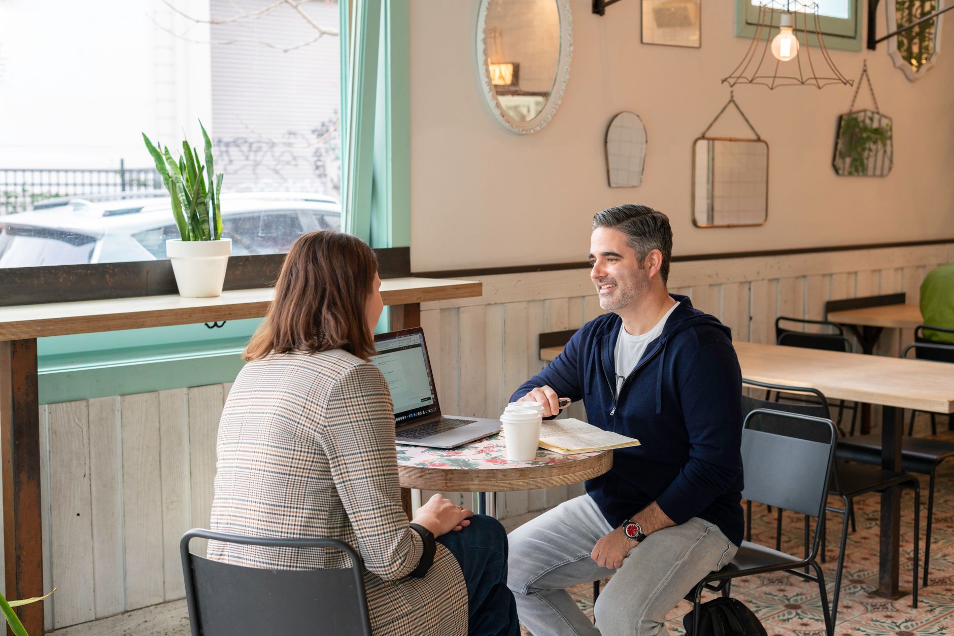Two small business owners talking over coffee at a table