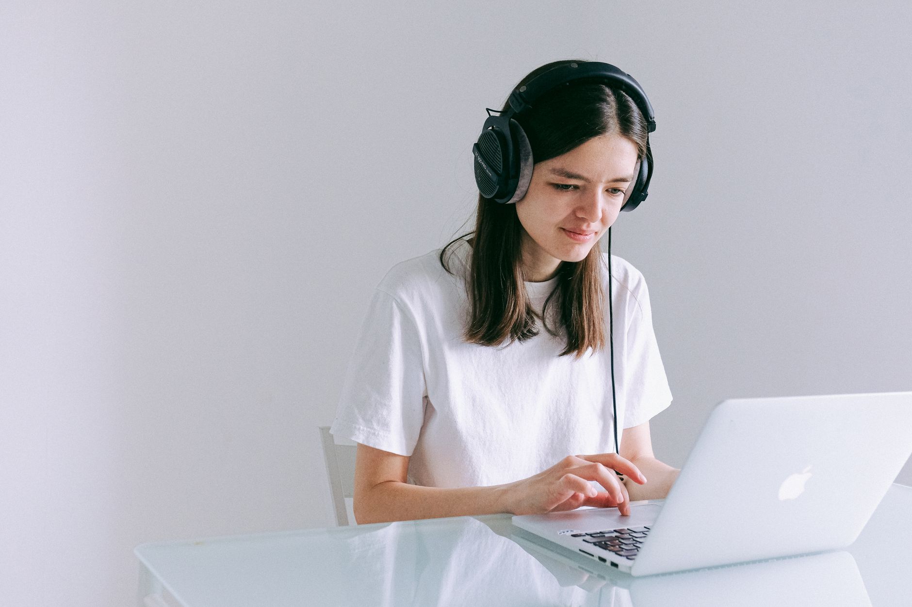 A freelancer wearing a headset working at a laptop in a home workspace