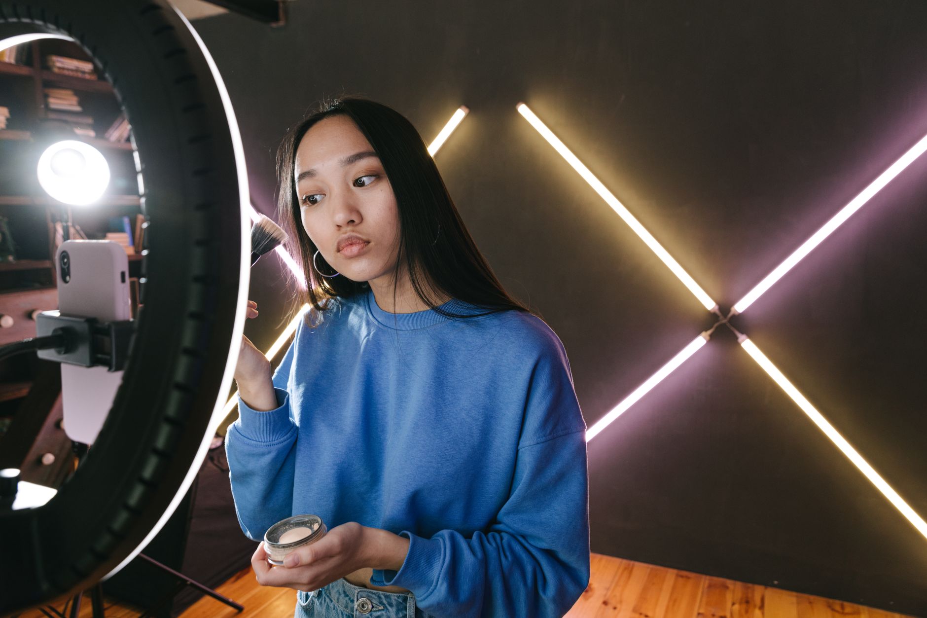 A woman filming a short tutorial with her phone and a ring light at home