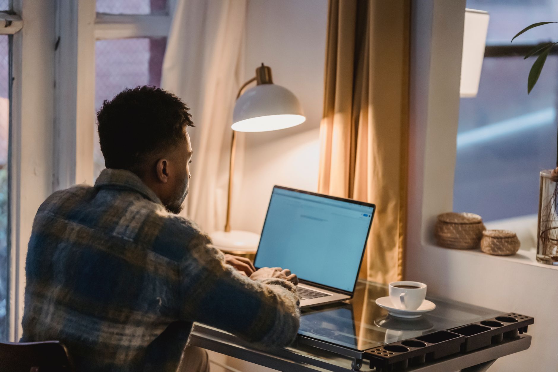 A man working at a kitchen table in the evening with a coffee, planning a side hustle around his day