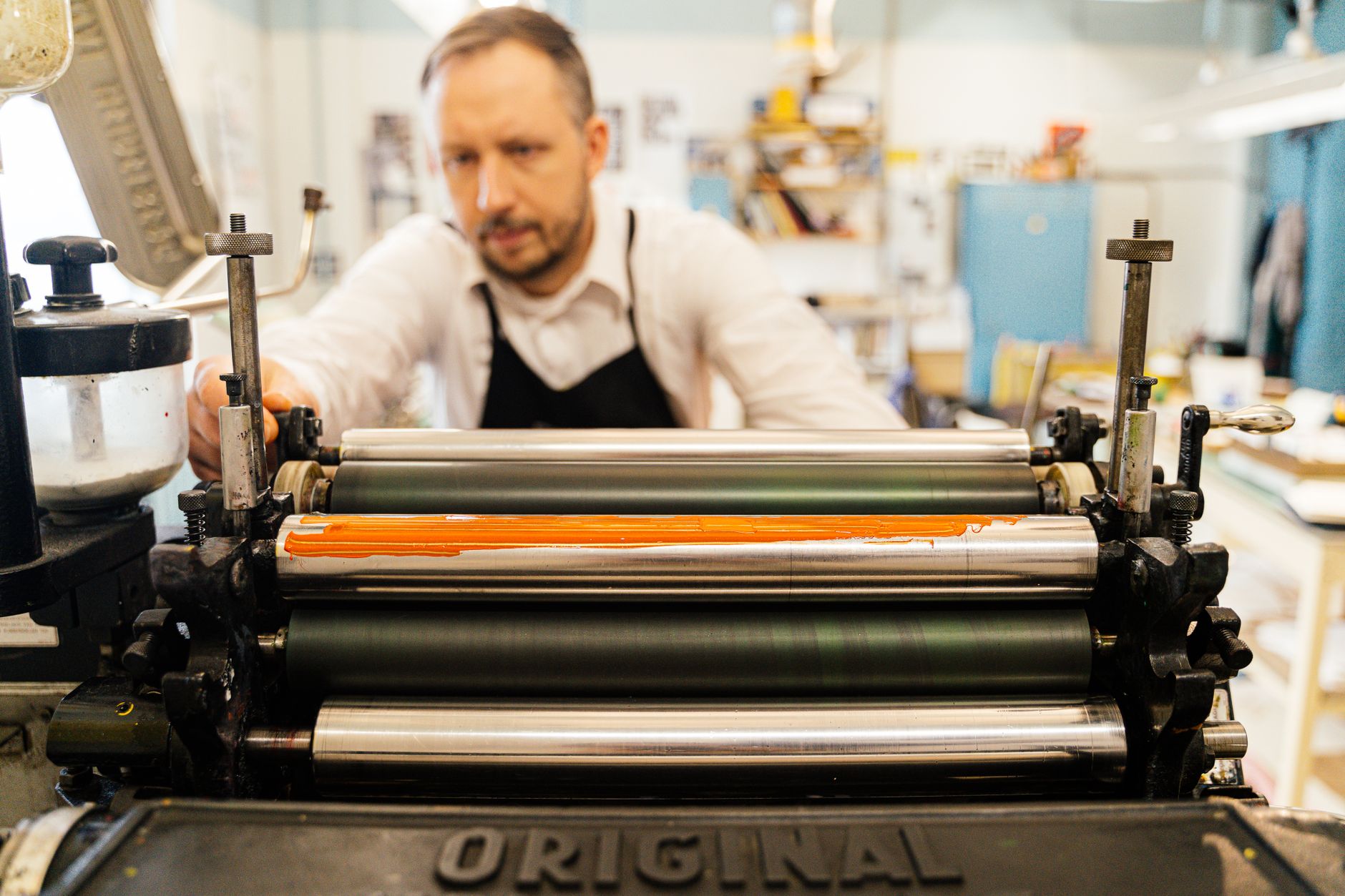 A letterpress printer working under a sign that has stayed the same for years