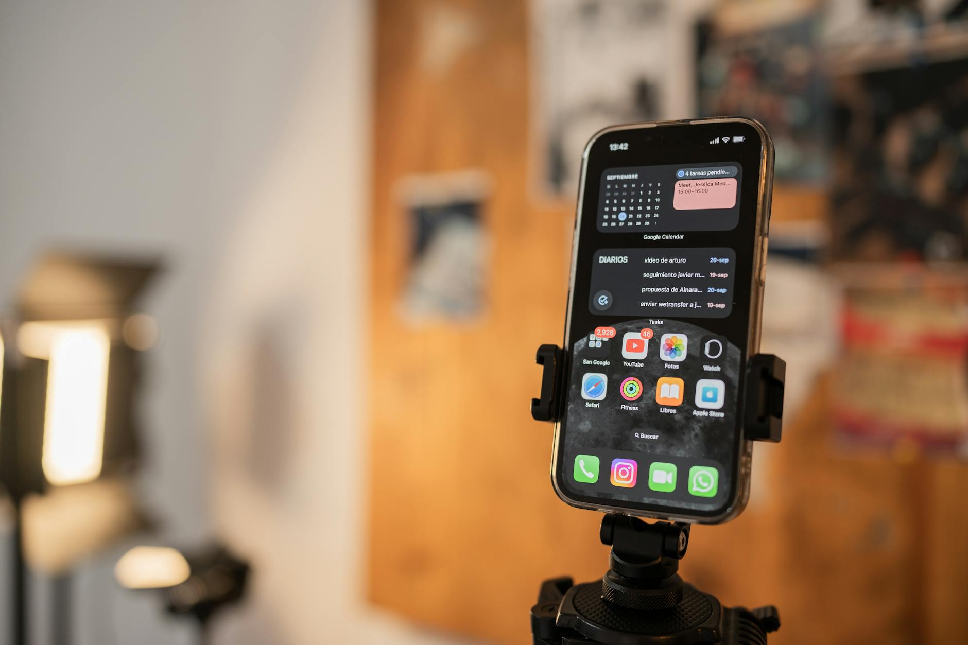 Close-up of a smartphone held on a tripod indoors with apps displayed on screen.